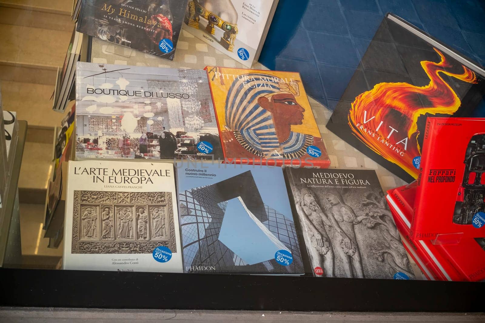 Cremona, Italy - November 27th 2024 Various books on art, architecture, history, and culture are displayed in a bookshop window, with a 50% discount sticker