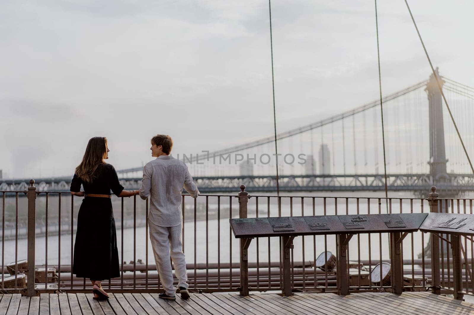 A beautifully romantic moment was captured between an affectionate couple, framed by a stunning bridge backdrop. Manhattan and Brooklyn bridge in New York.