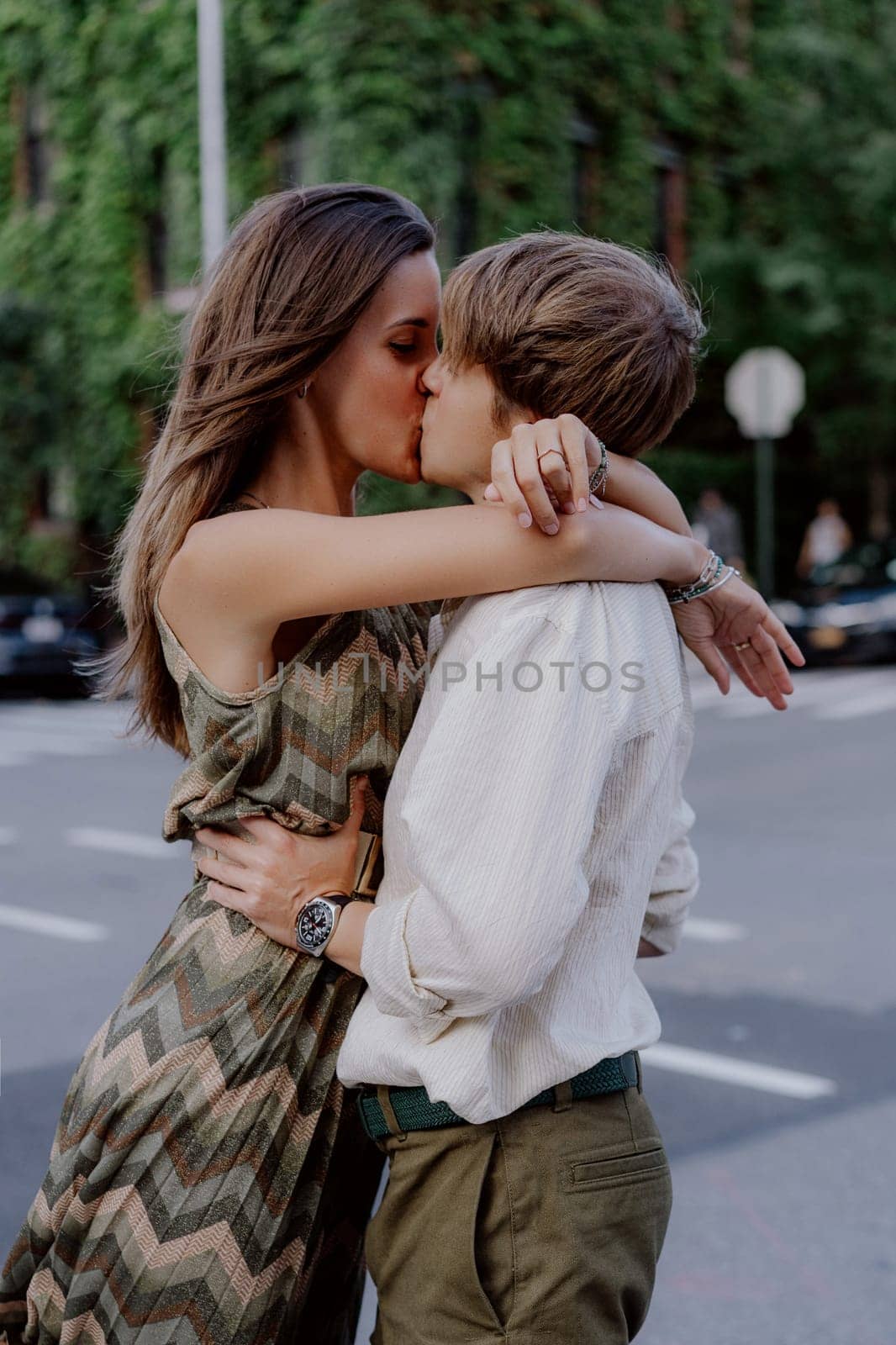 A romantic moment is captured between a couple in a vibrant urban setting filled with lush greenery