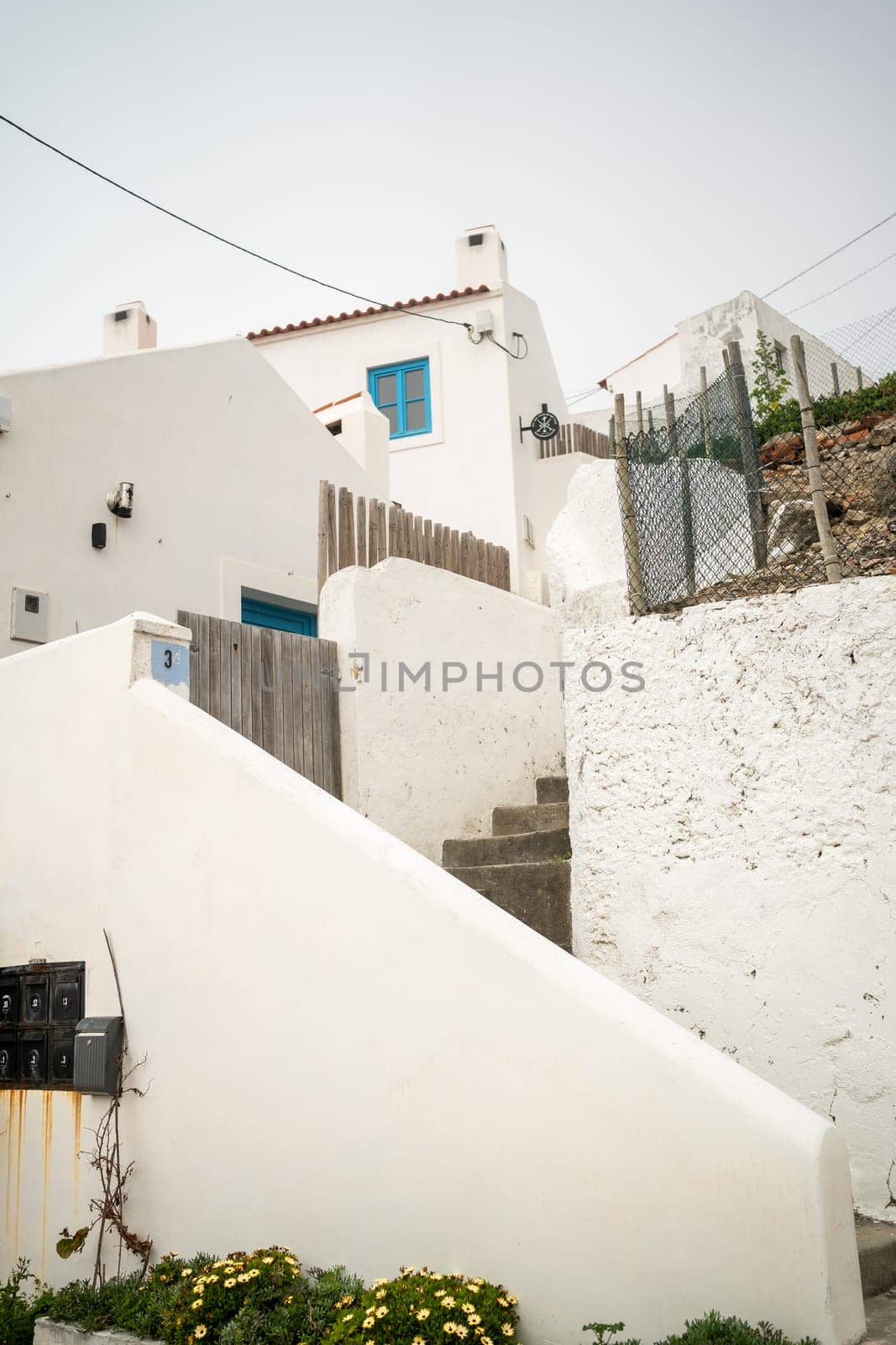 From below of white houses and steps in small town of Portugal. Low angle shot of small buildings against clear sky during daytime.