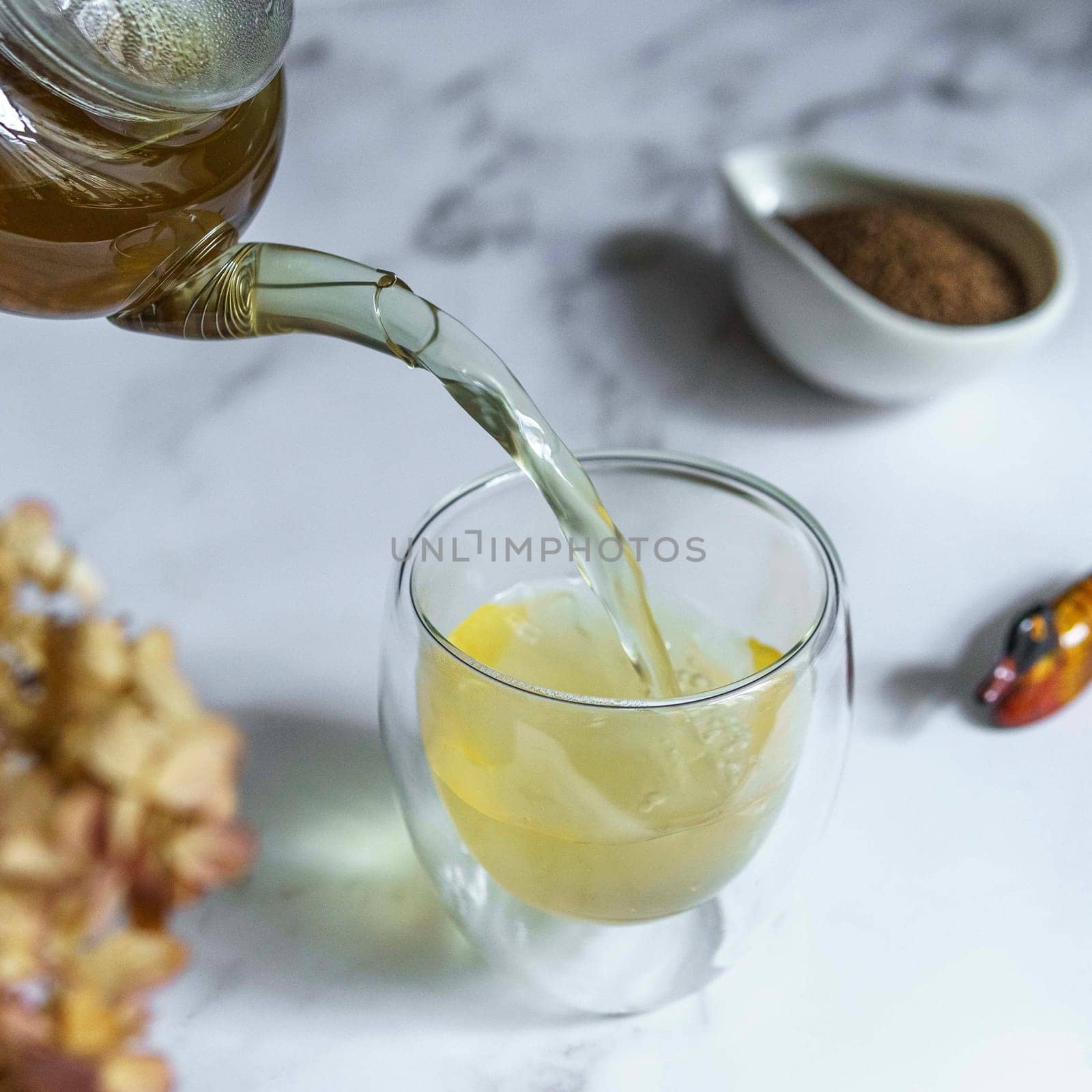 A breathtaking view of fragrant herbal tea being elegantly poured into a clear glass, surrounded by aromatic spices