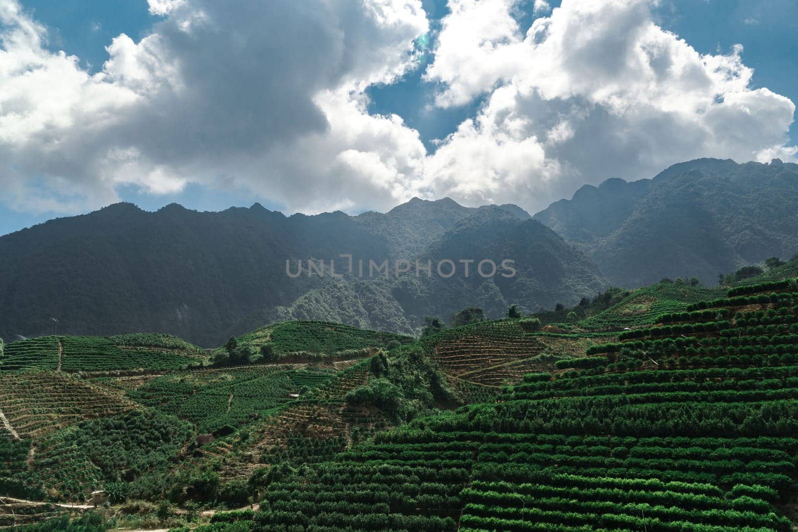 A truly breathtaking view of terraced green hills set against majestic mountains and an expressive, vibrant sky