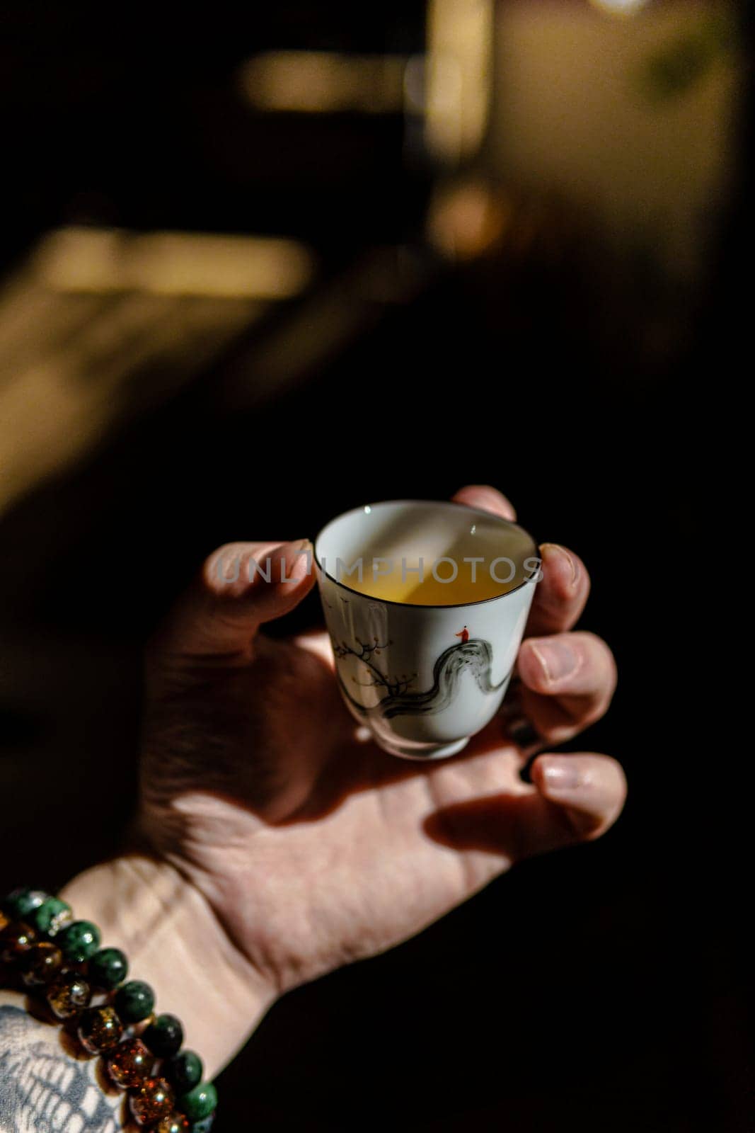 A tranquil moment in a soothing atmosphere with a hand holding a delicate tea cup, illuminated by warm light