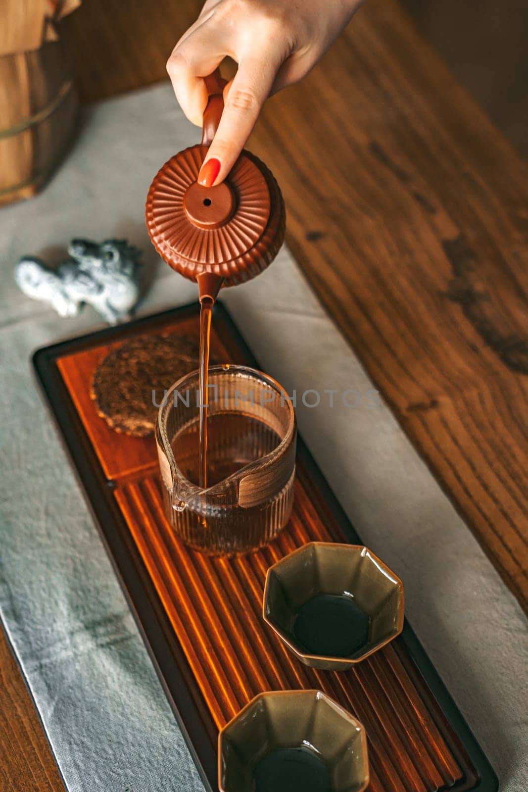 A beautifully serene scene that showcases the art of tea pouring with elegant, refined teaware on a wooden table