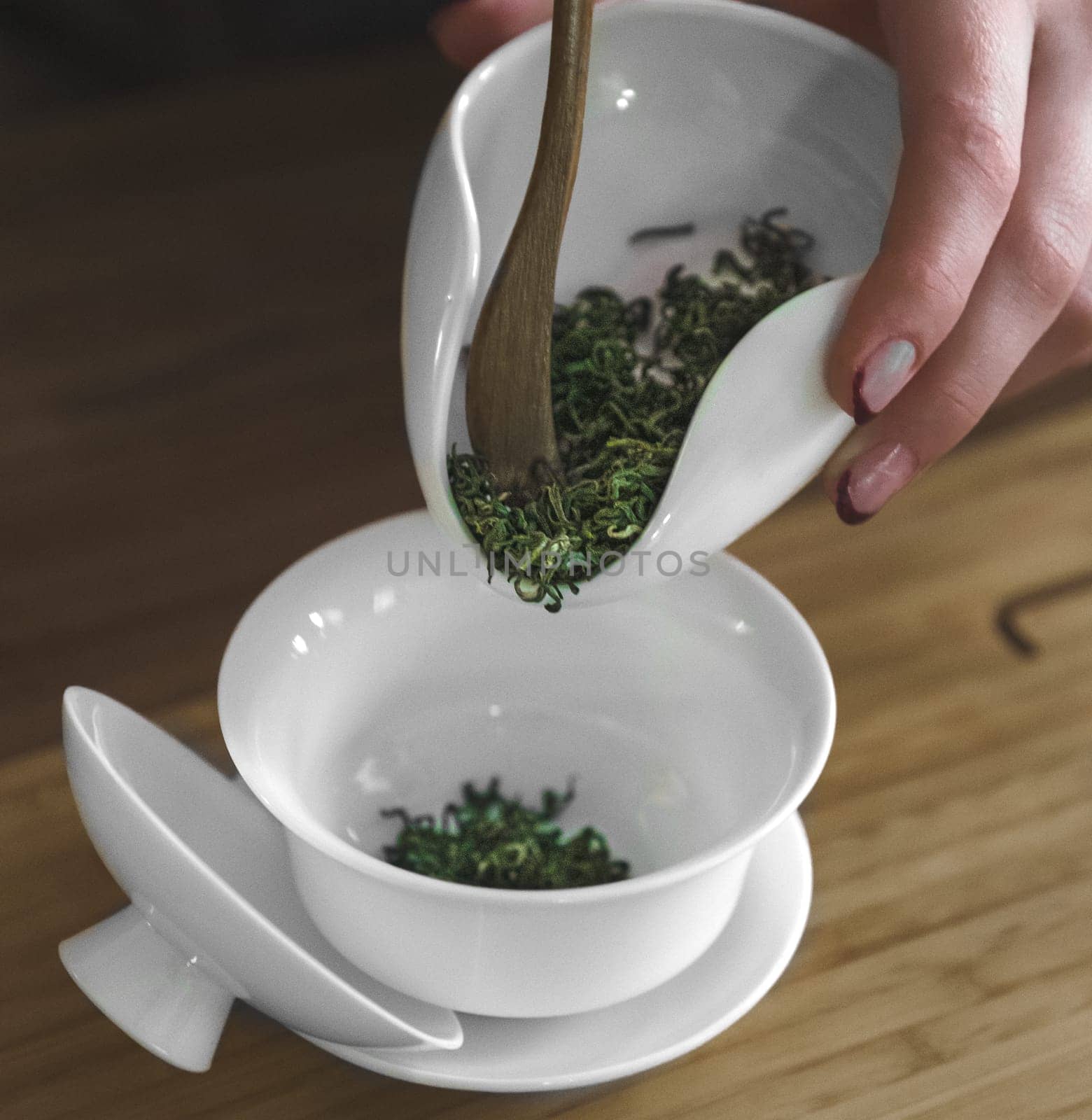 A skilled hand gracefully pours fresh, vibrant herbs into a chic white bowl in preparation for a delightful herbal tea