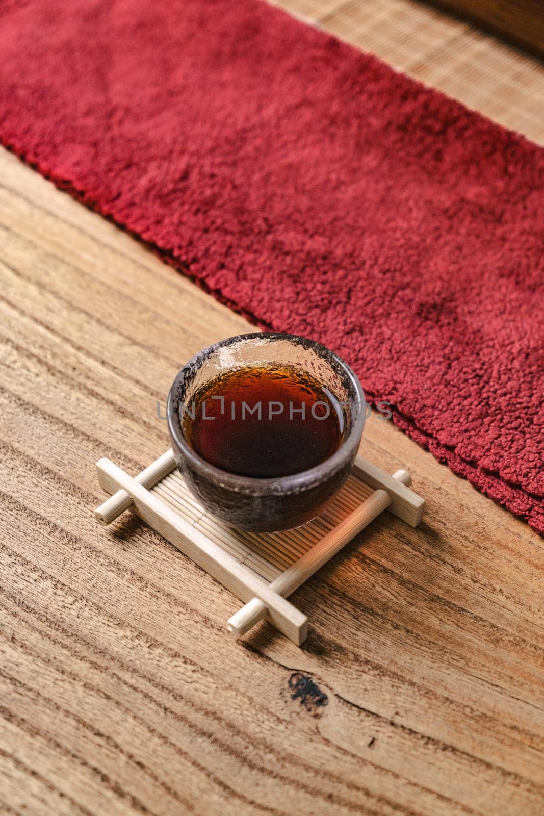 A beautifully stylish tea cup elegantly placed on a wooden tray, surrounded by rich, textured red fabric