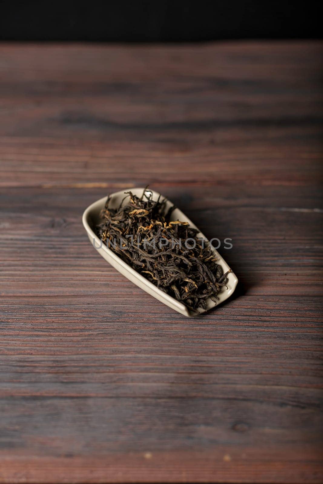 An exquisite artistic arrangement of loose leaf tea presented elegantly in a ceramic dish placed on rustic wood