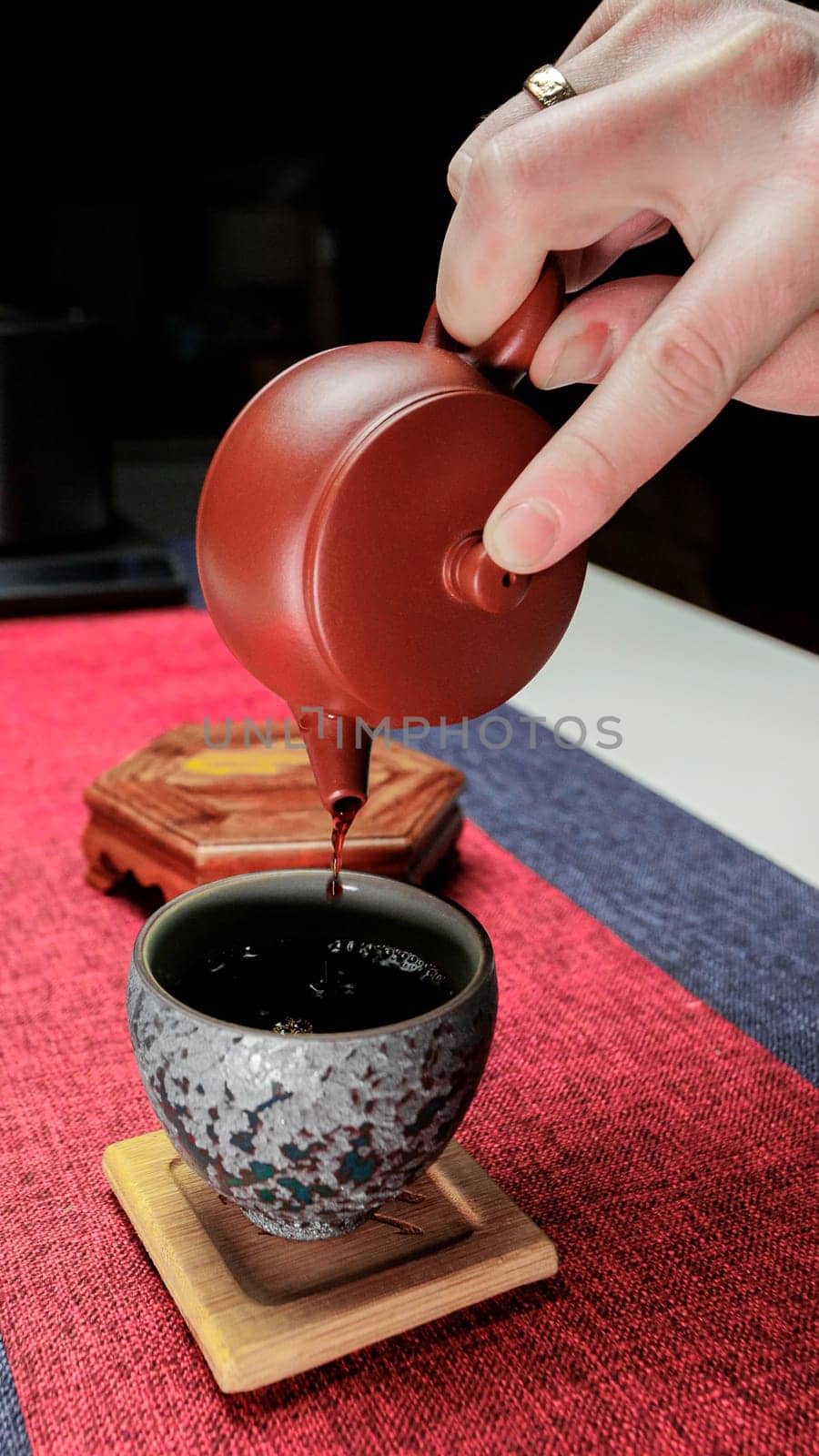 A tranquil moment beautifully illustrating the art of pouring tea from a charming clay teapot into a decorative cup