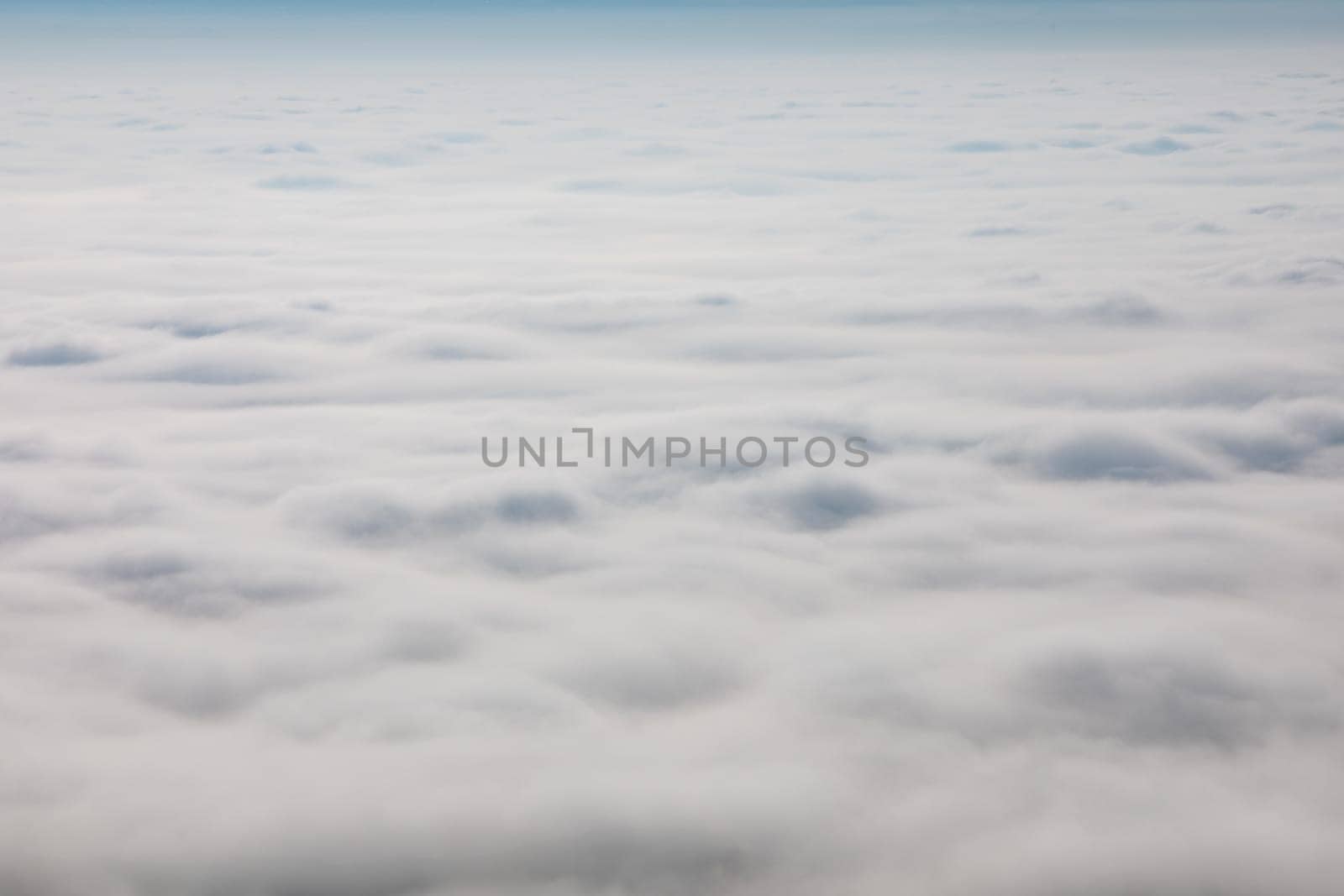 A vast expanse of low-lying clouds blankets the landscape. The view, likely from an airplane, shows a dense layer of fog or stratus clouds. No people are visible.