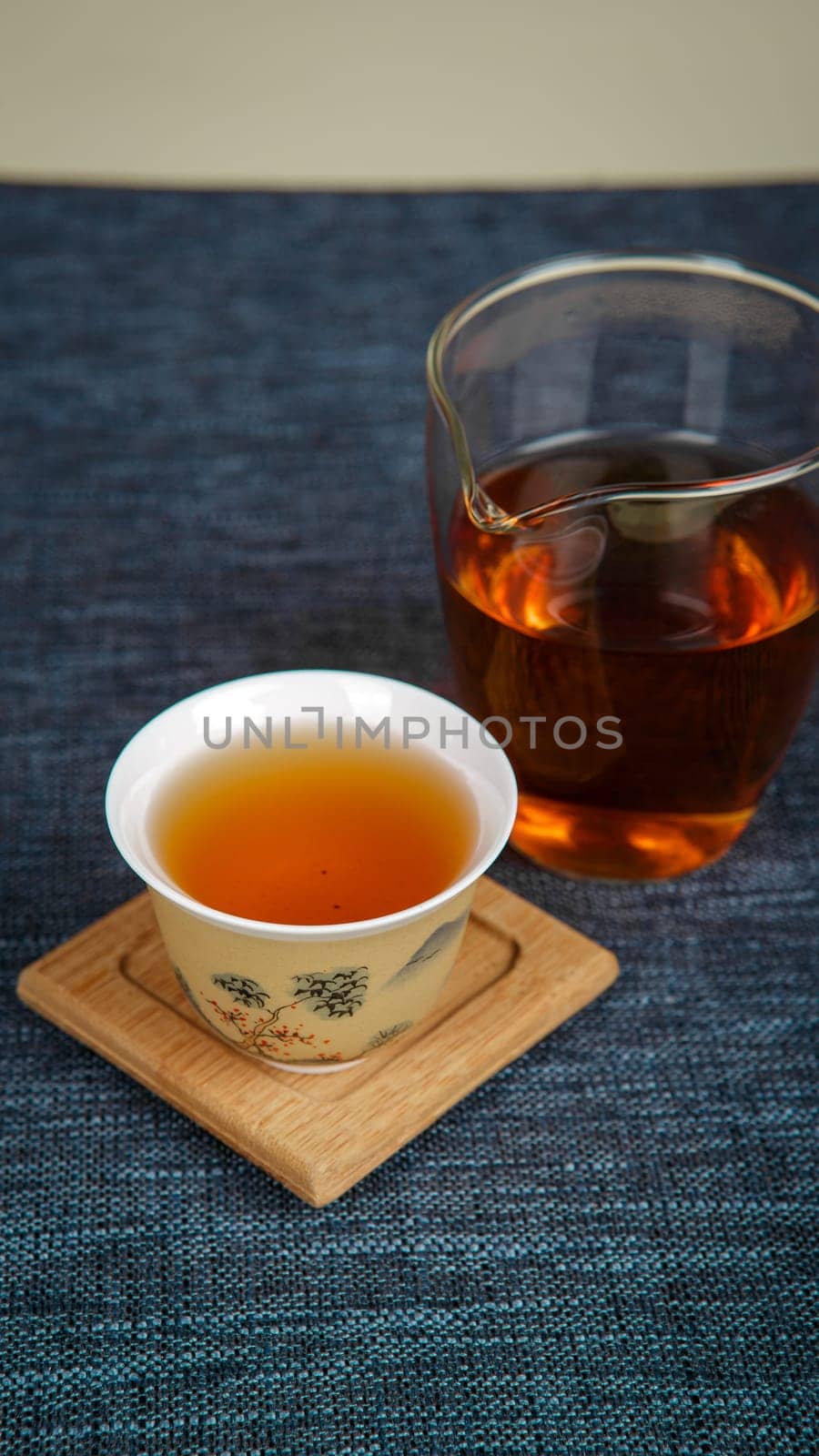An elegant tea presentation with a traditional cup and modern glass, beautifully arranged on a textured surface