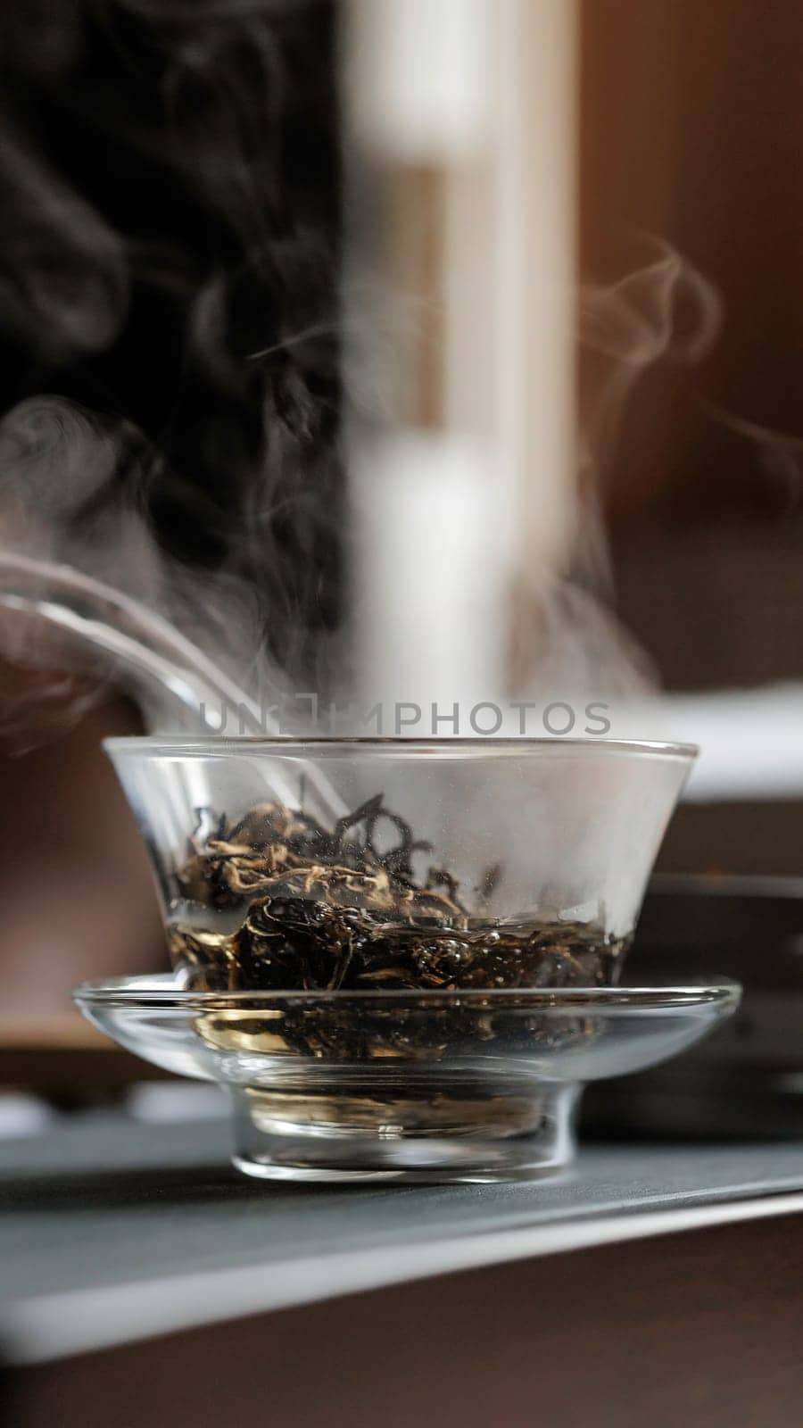 A calm and serene scene of steaming loose leaf tea expertly brewing in a beautiful glass bowl, inviting warmth