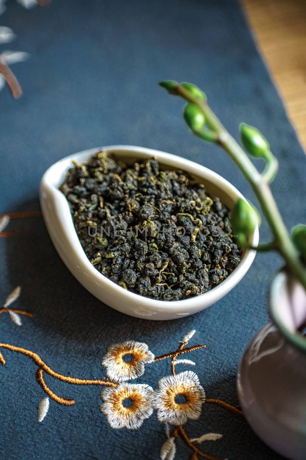 An attractive arrangement of fresh green tea leaves in a decorative bowl, set against a vibrant floral background