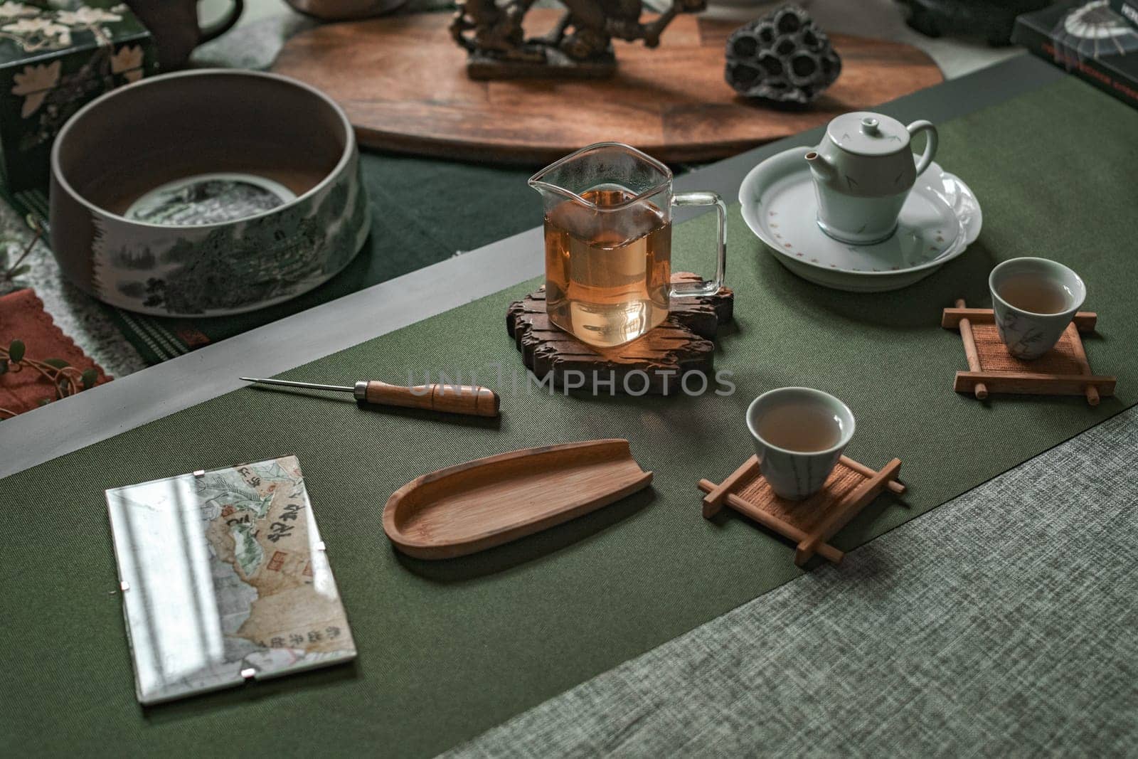A serene tea setup featuring traditional teacups, an elegant teapot, and accessories on a textured mat