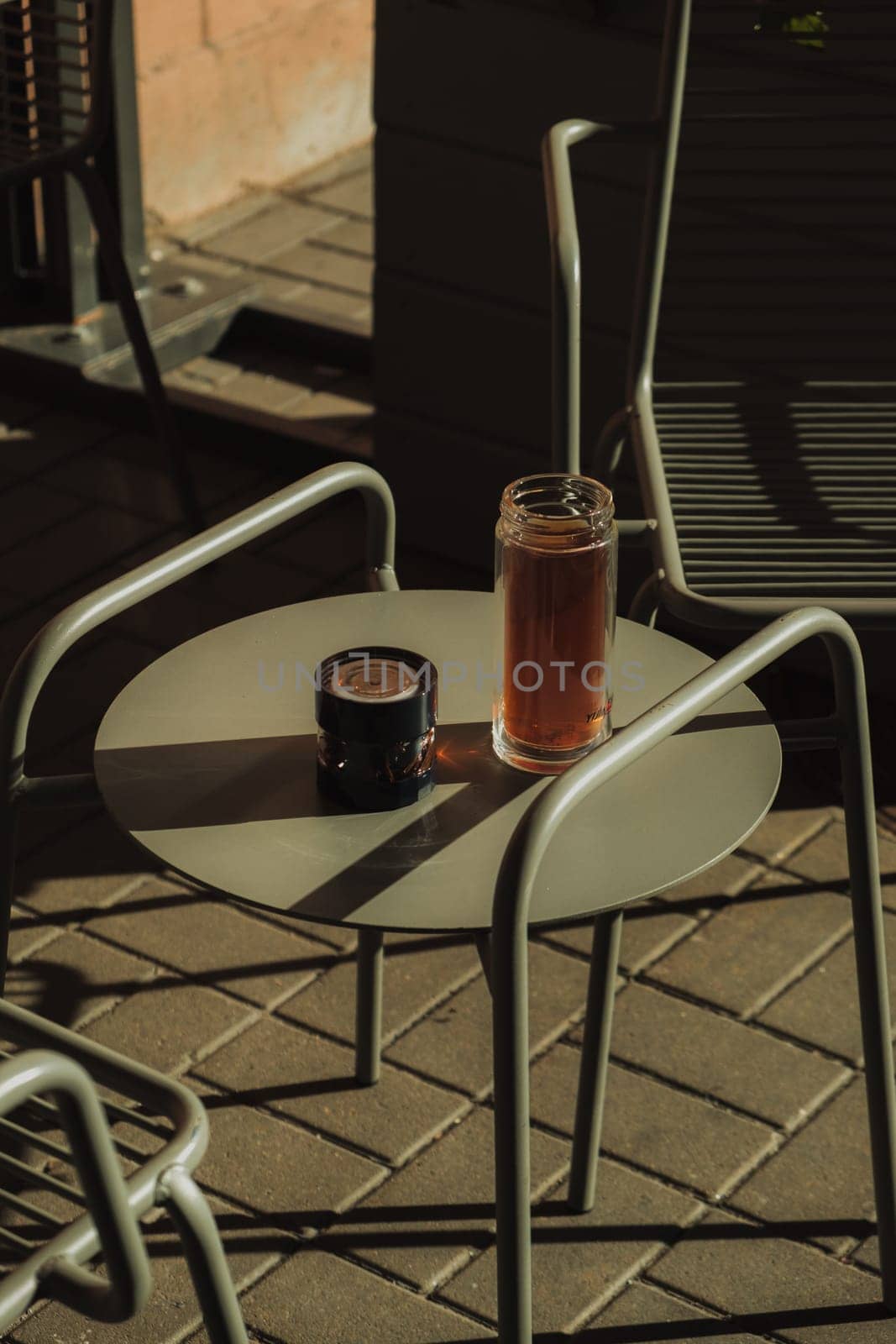 A cozy outdoor setting that features a glass of coffee and a candle elegantly placed on a minimalist table