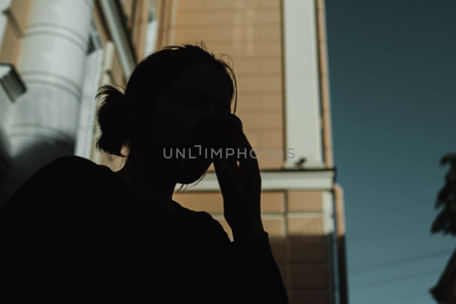 A shadowy figure, lost in deep contemplation and thought, stands against a striking and vibrant urban backdrop