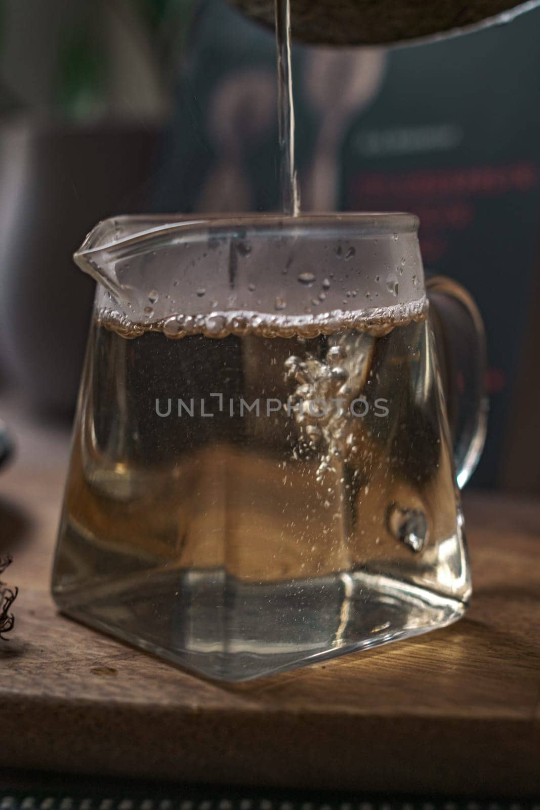 A captivating closeup of aromatic tea being elegantly poured into a stylish geometric teapot, showcasing bubbles