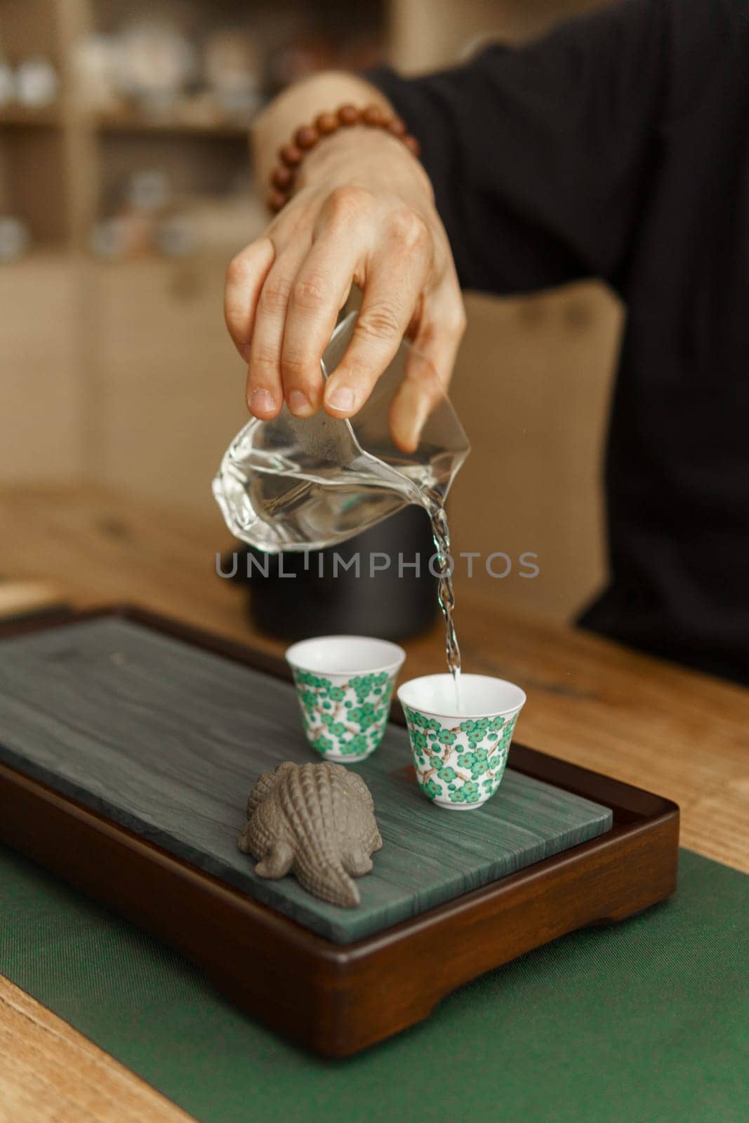 A skilled hand pours aromatic tea into ceramic cups, showcasing craftsmanship in a calm, traditional ceremony