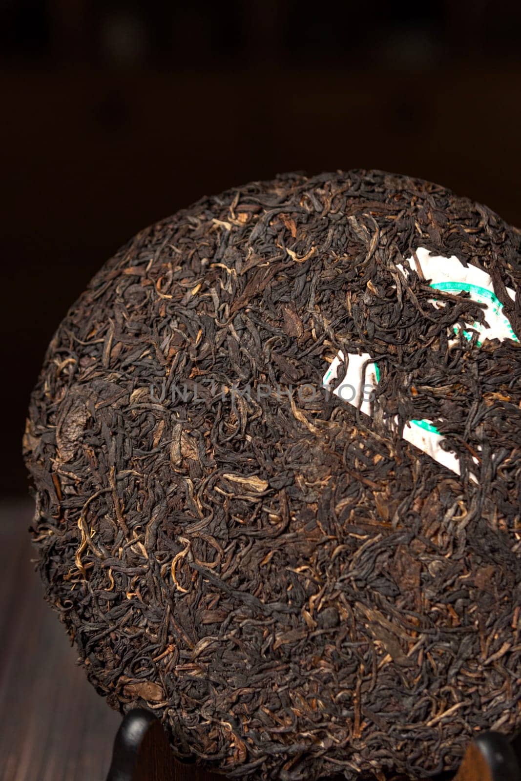 This is a detailed view of a round, compressed tea cake that beautifully showcases its intriguing texture and leaves