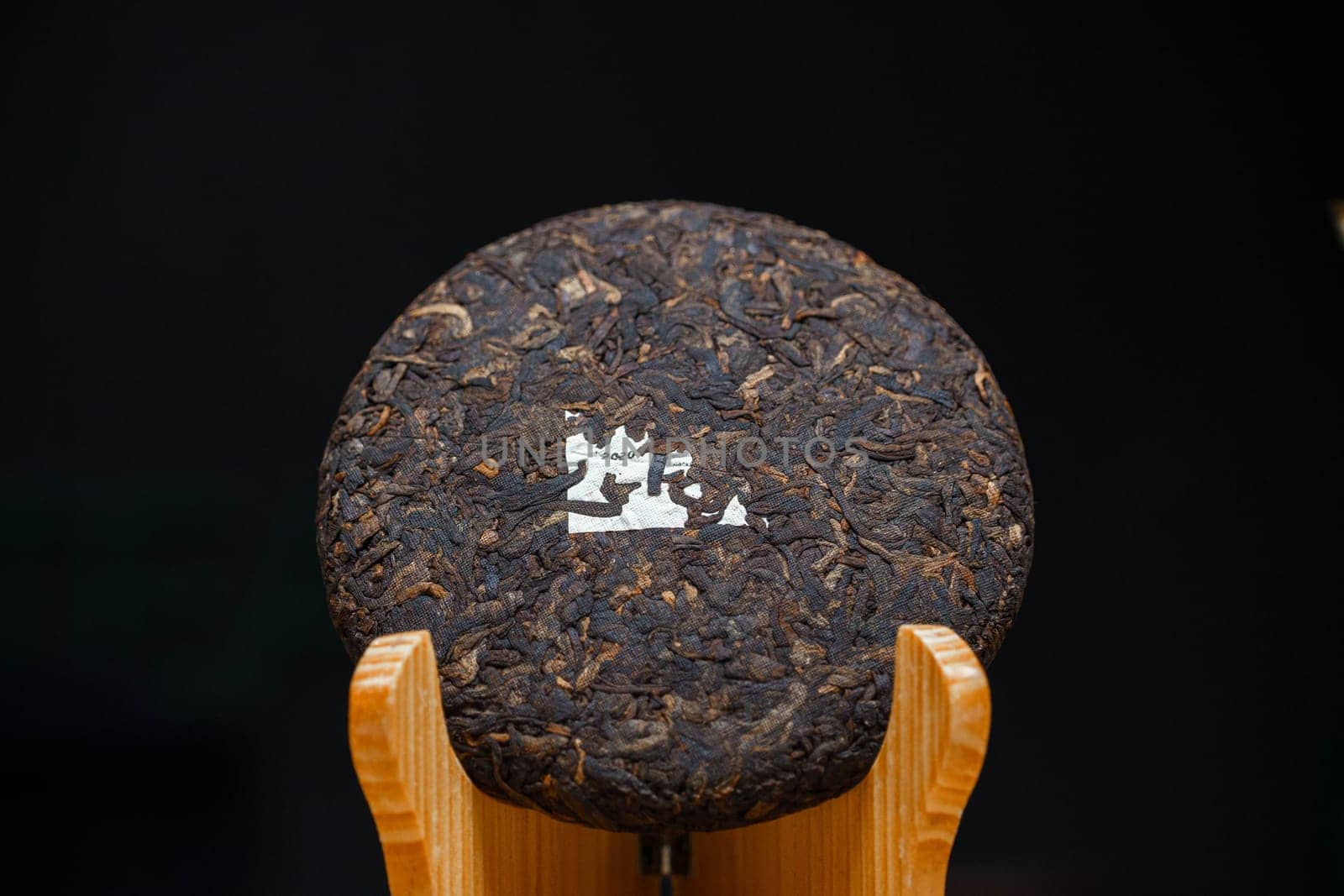 A beautifully crafted round compressed tea cake is on display, showcasing its unique texture and artistry
