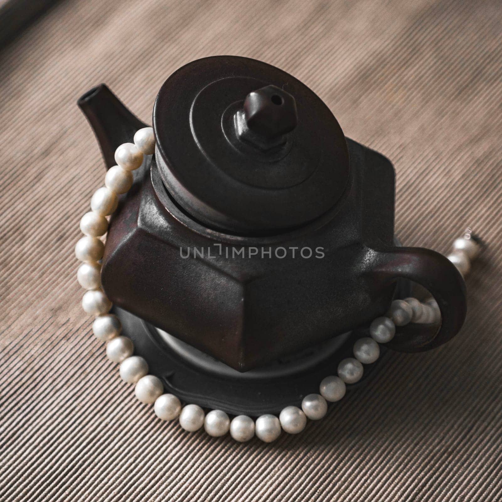A stylish black teapot adorned with pearls, showcasing exceptional craftsmanship and stunning detail