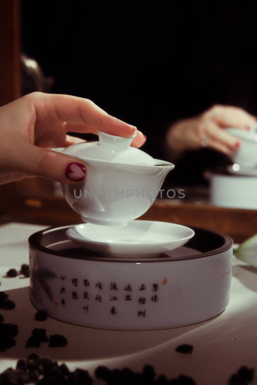 A serene tea ceremony that beautifully displays a hand pouring tea from exquisitely crafted porcelain pieces