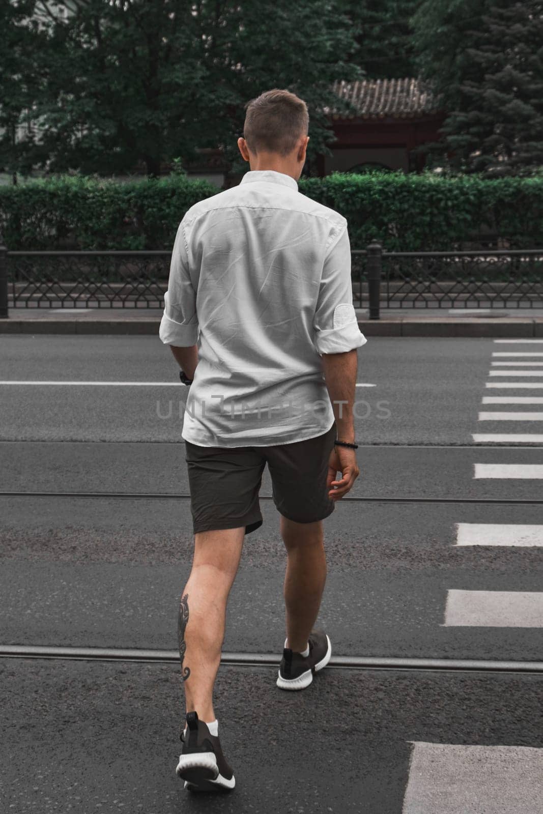 A man strolls across a busy street, showcasing a mix of urban fashion and an active outdoor lifestyle