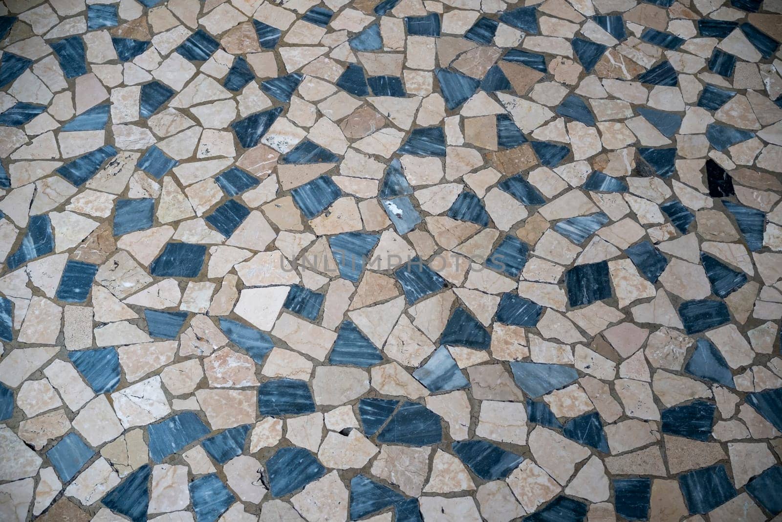 Cremona, Italy - November 27th 2024 Close-up of a decorative pavement made with irregular beige and blue marble stones forming a geometric pattern in cremona, italy