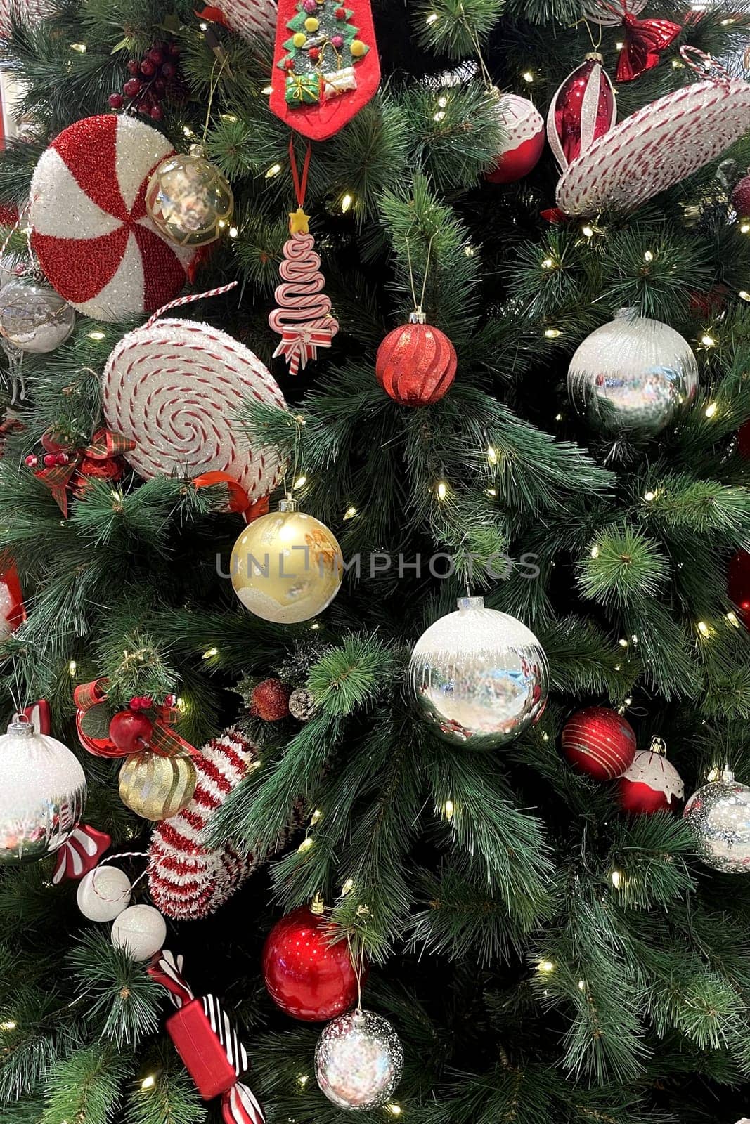 Festive Christmas Tree with Ornaments.The image shows a beautifully decorated Christmas tree adorned with a variety of ornaments. The tree is lush with green branches and is illuminated by small white lights.