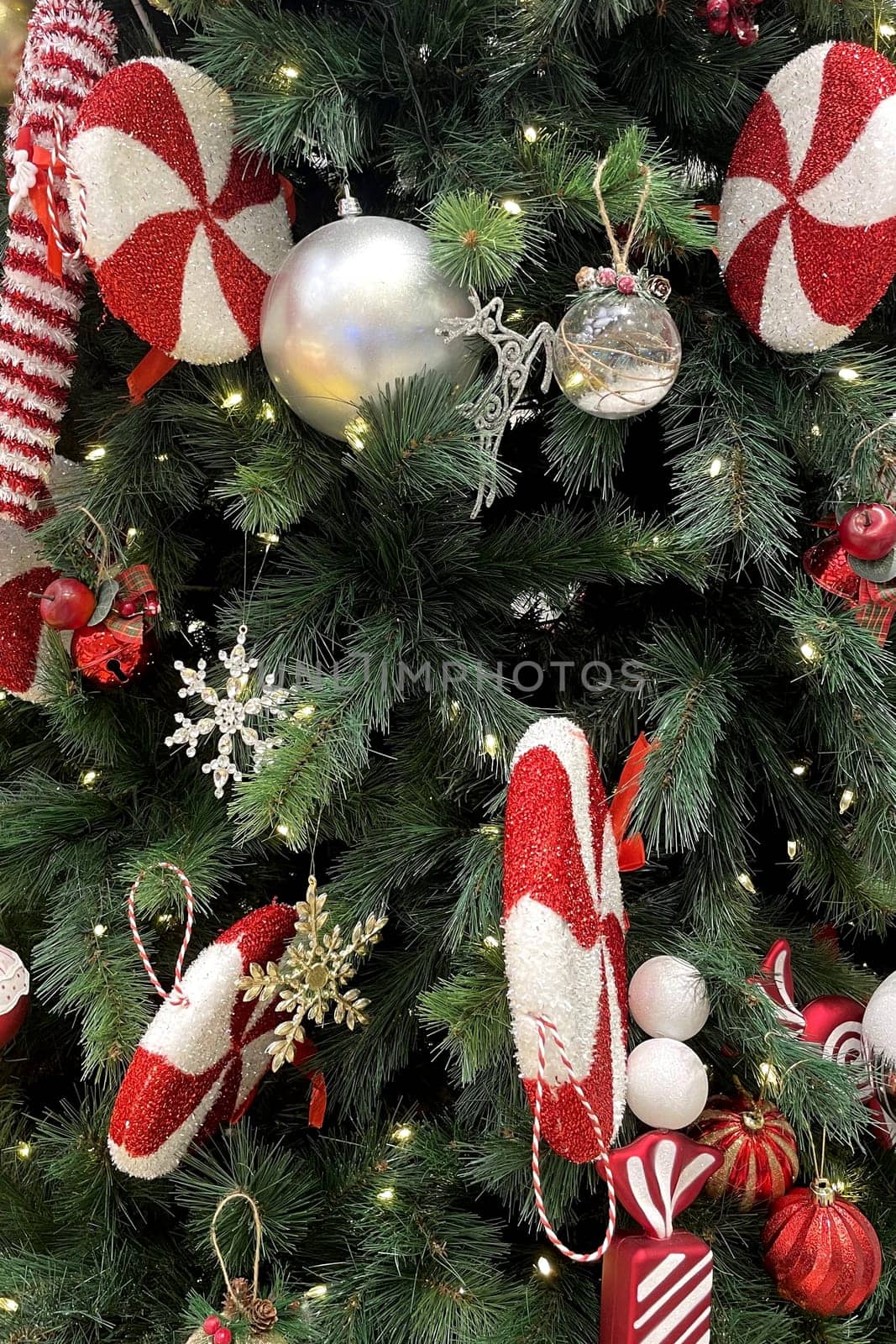 Festive Christmas Tree with Ornaments.The image shows a beautifully decorated Christmas tree adorned with a variety of ornaments. The tree is lush with green branches and is illuminated by small white lights.