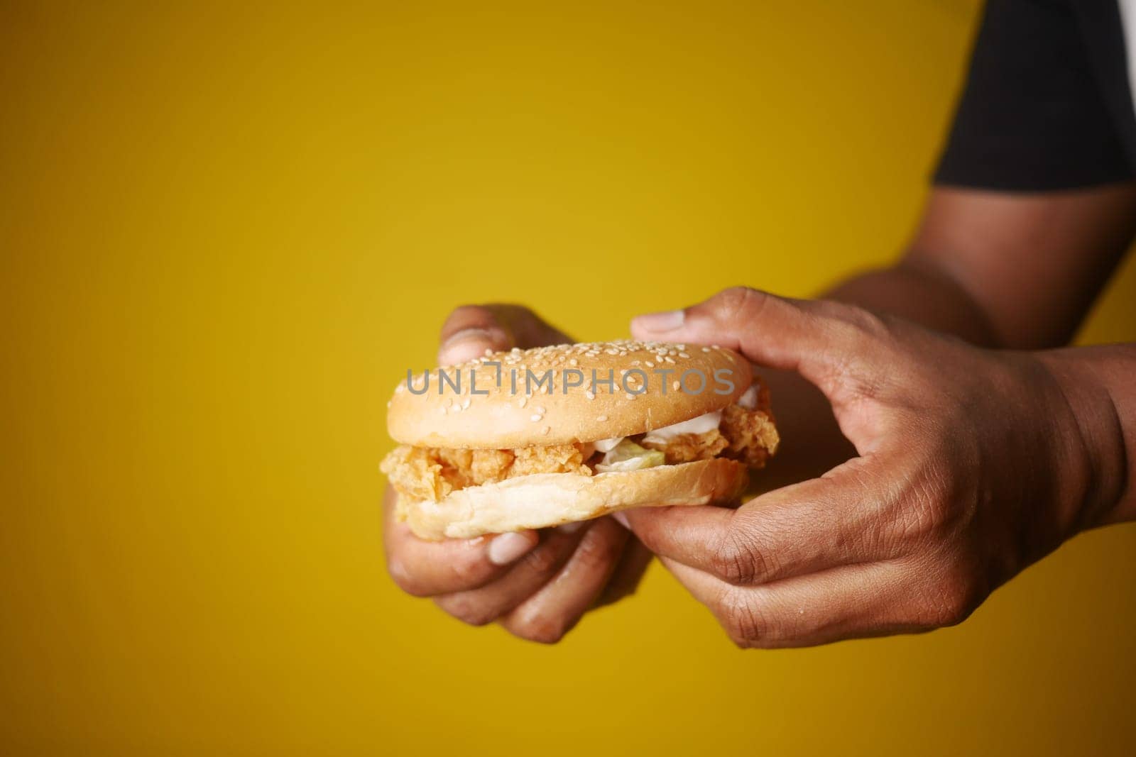 A tasty fried chicken sandwich is against a bright yellow backdrop, enhancing its appeal