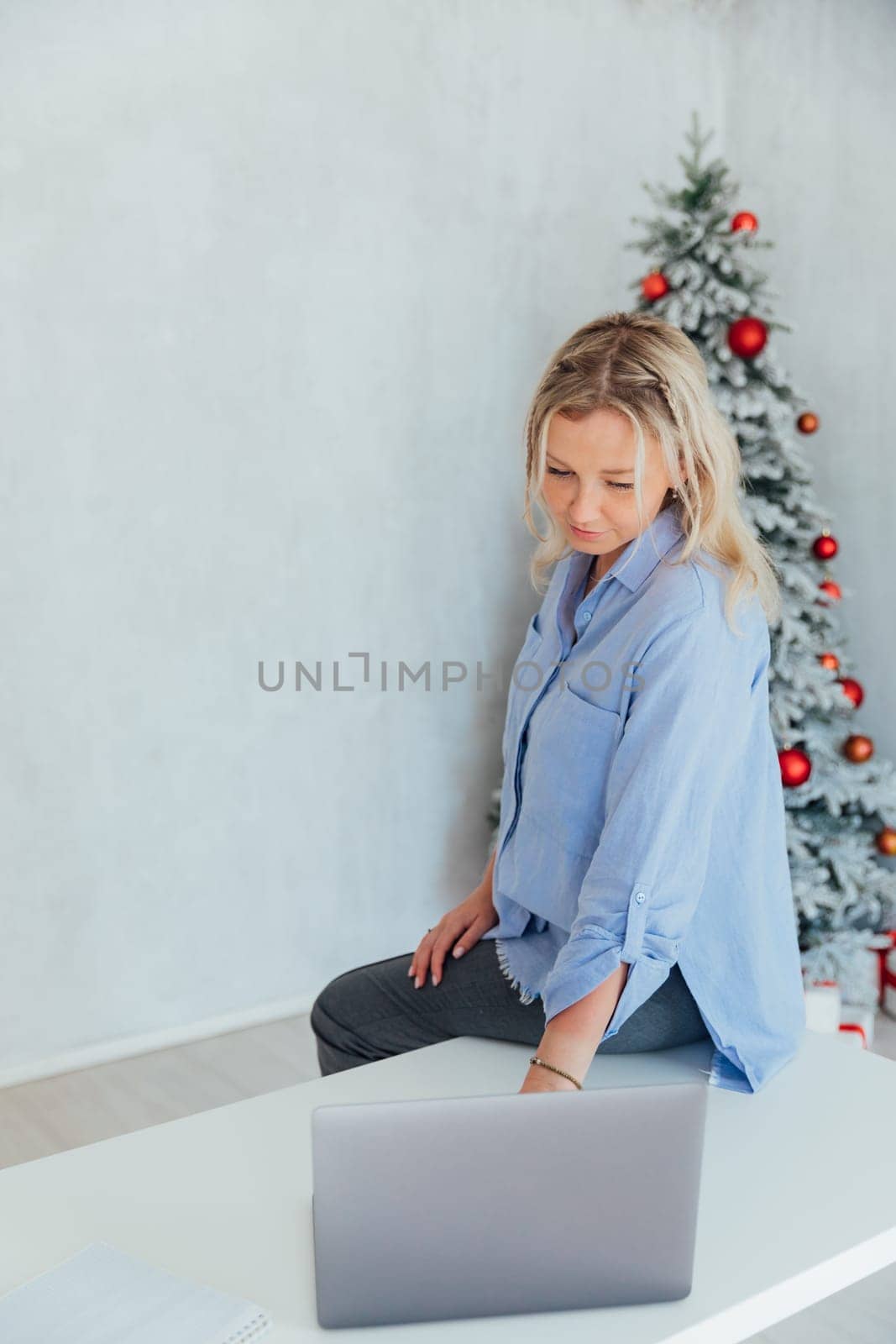 Business woman with laptop online at the christmas tree