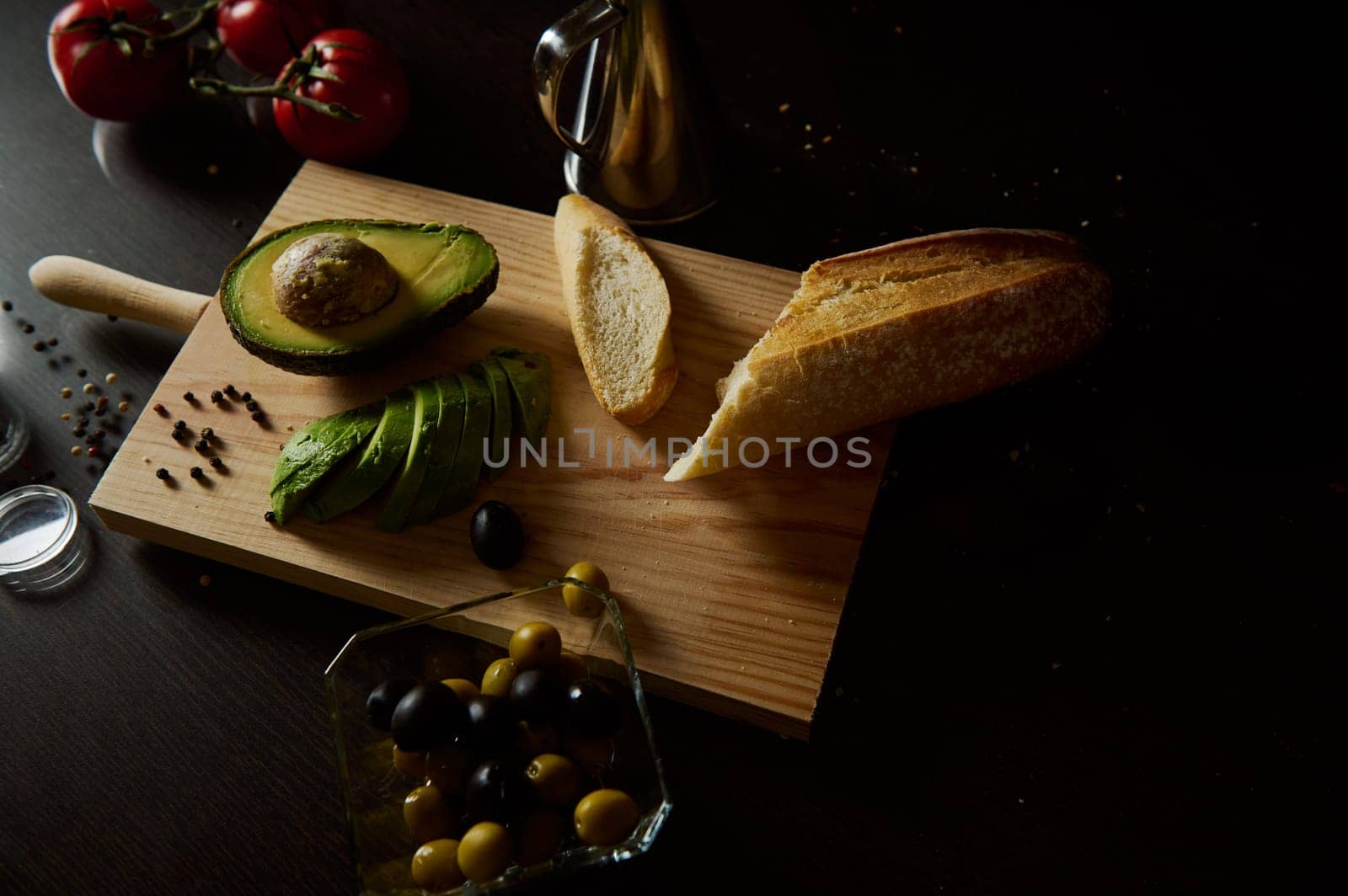 A wooden board displaying fresh ingredients including bread, avocado, and olives. Perfect for culinary inspiration and food preparation settings.