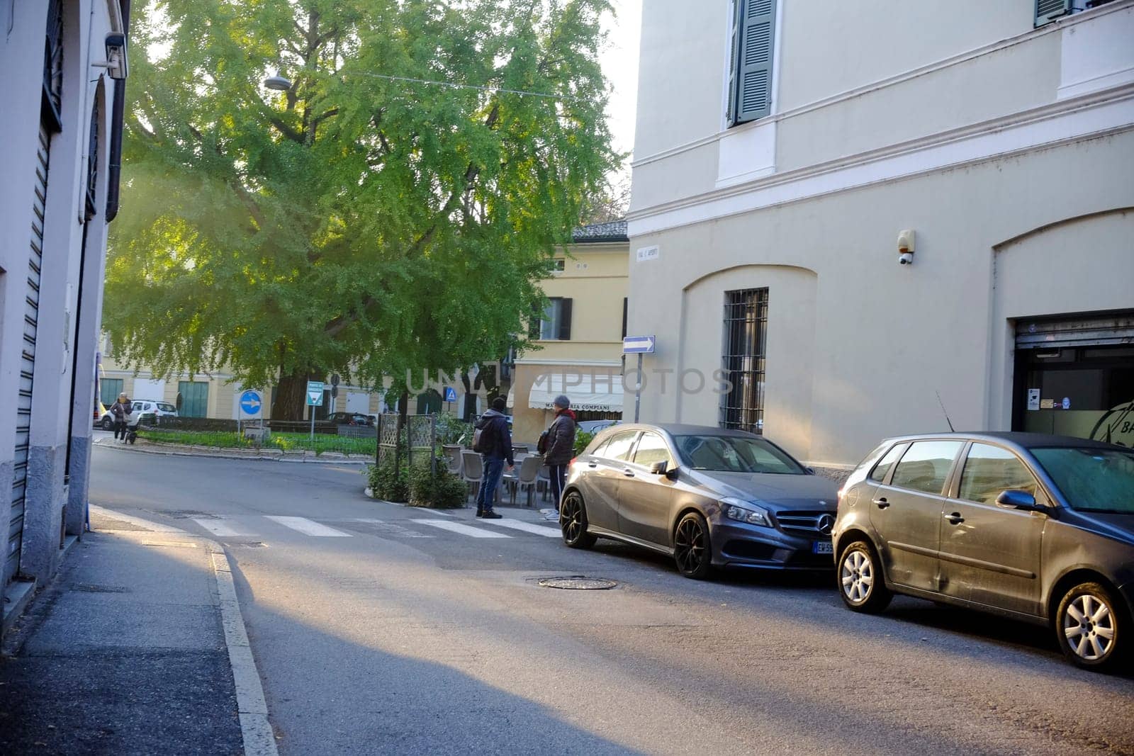 Cremona, Itally - October 6th 2024 Mercedes-benz a 200 cdi parked near a crosswalk with pedestrians walking in an urban street next to a large tree