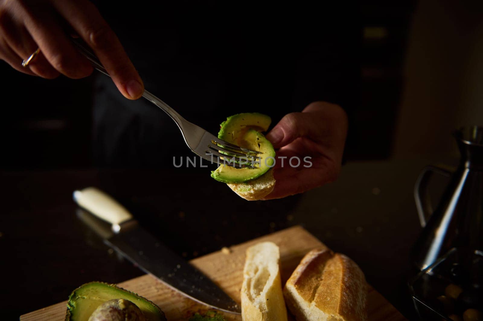 Close-up of hands preparing avocado slices for a fresh, healthy meal at home.