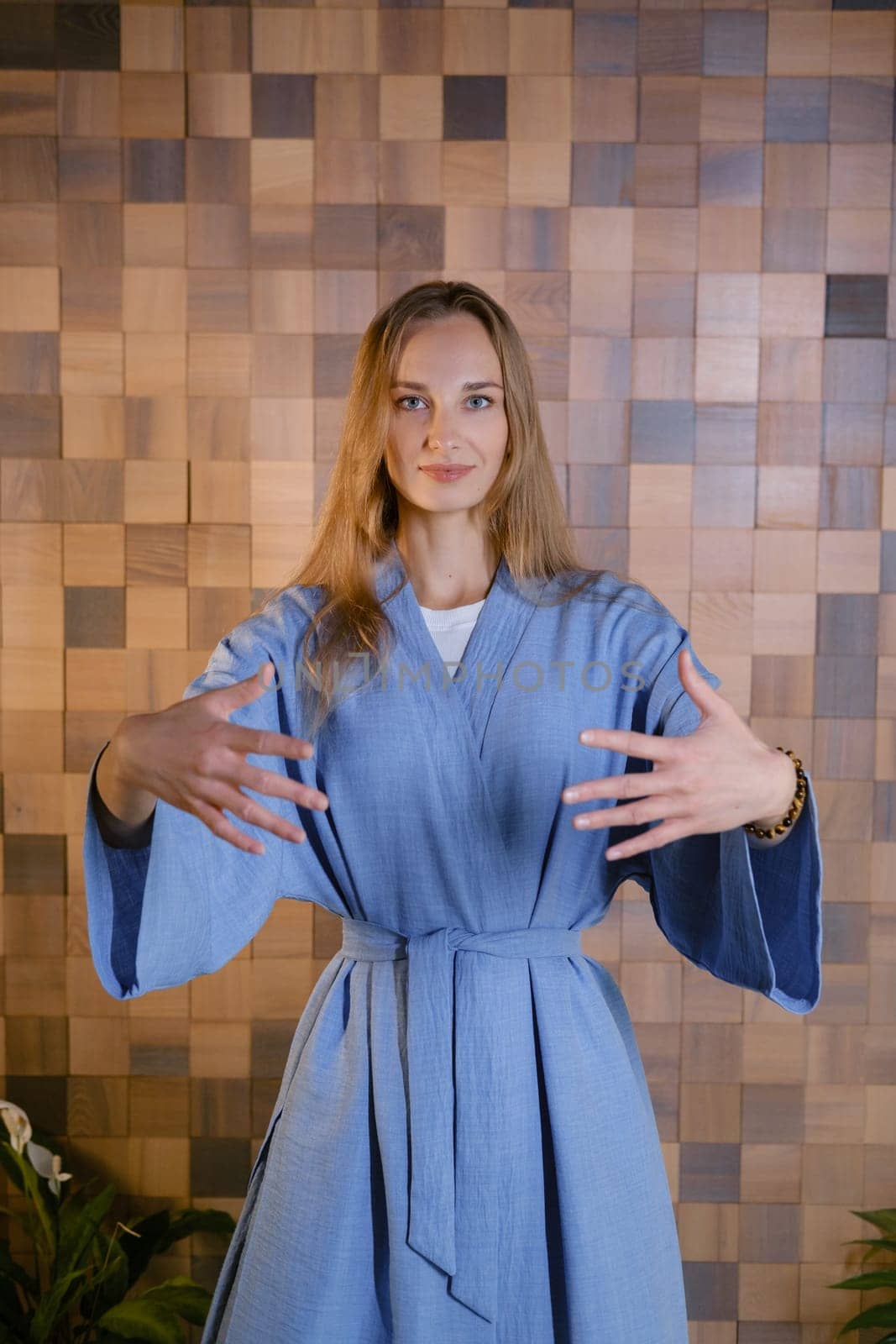 Yoga instructor in blue kimano at fitness gym . The girl does qigong yoga. The exercises are based on the movement of internal energy, the system of channels, energy centers, chakras.