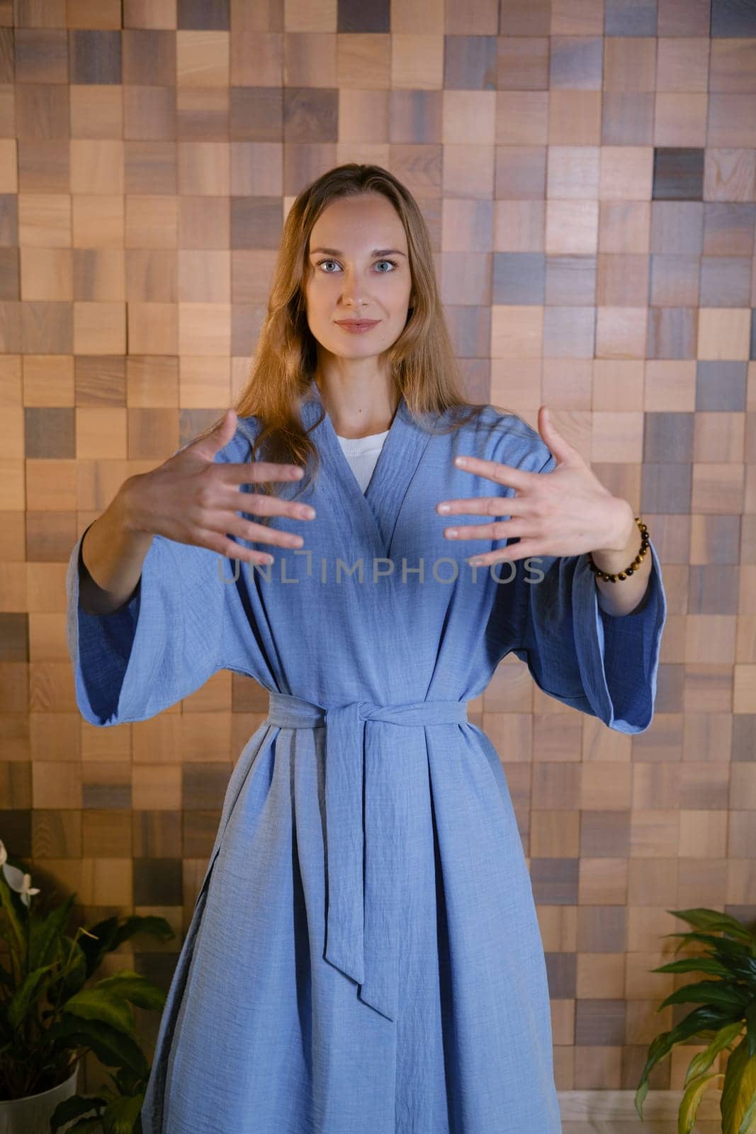 Girl in blue kimano practicing kundalini or qigong yoga in fitness gym . Spiritual energy, life force located at the base of the spine.