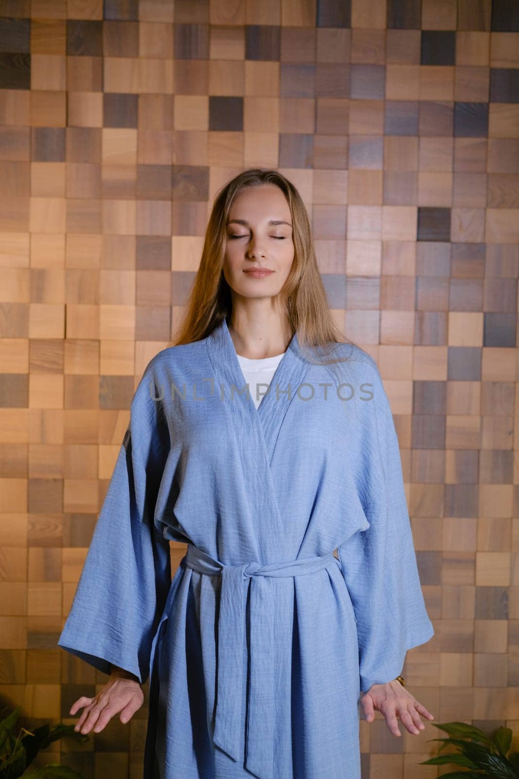 Yoga instructor in blue kimano at fitness gym . The girl does qigong yoga. The exercises are based on the movement of internal energy, the system of channels, energy centers, chakras.