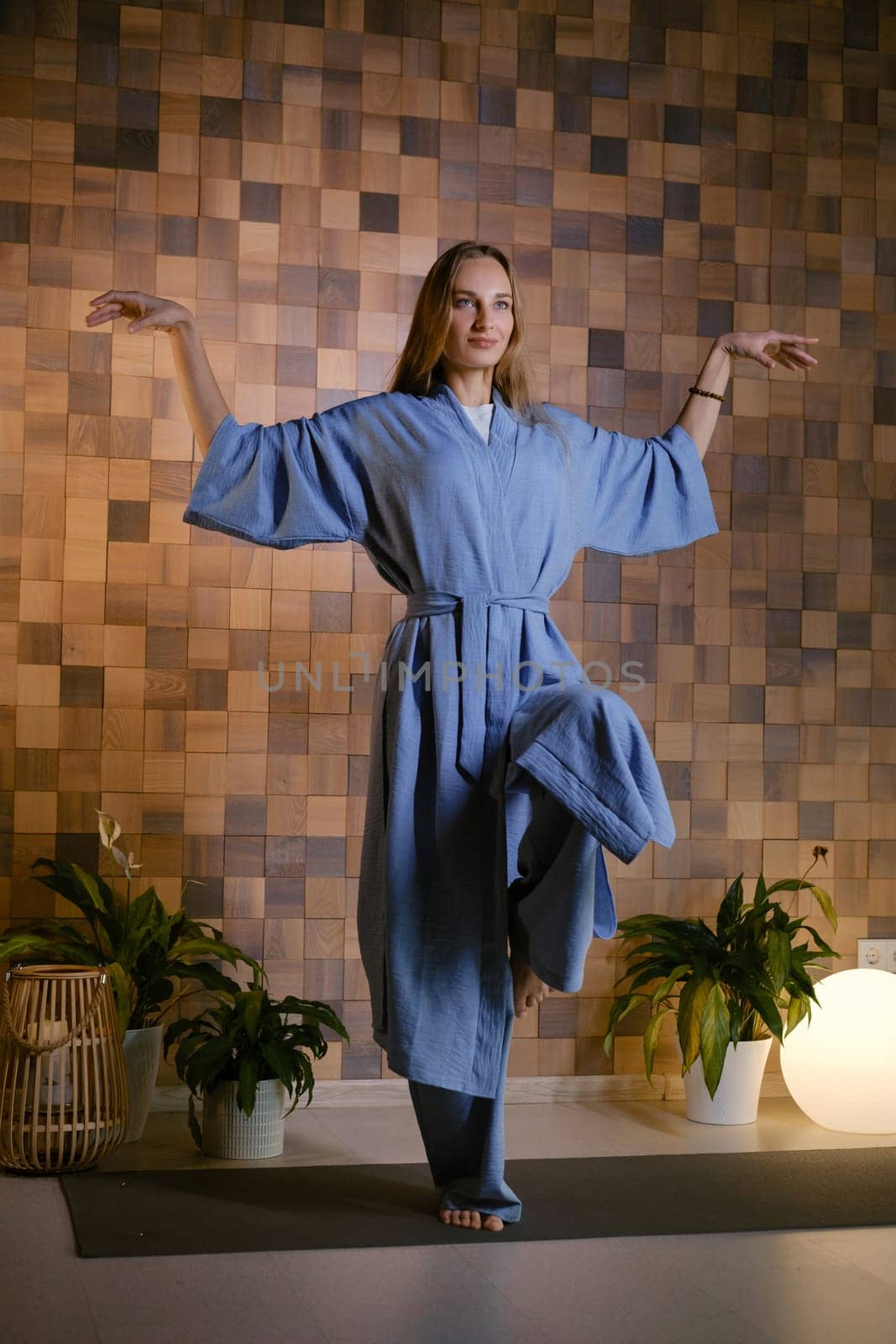 Girl in blue kimano practicing kundalini or qigong yoga in fitness gym . Spiritual energy, life force located at the base of the spine.