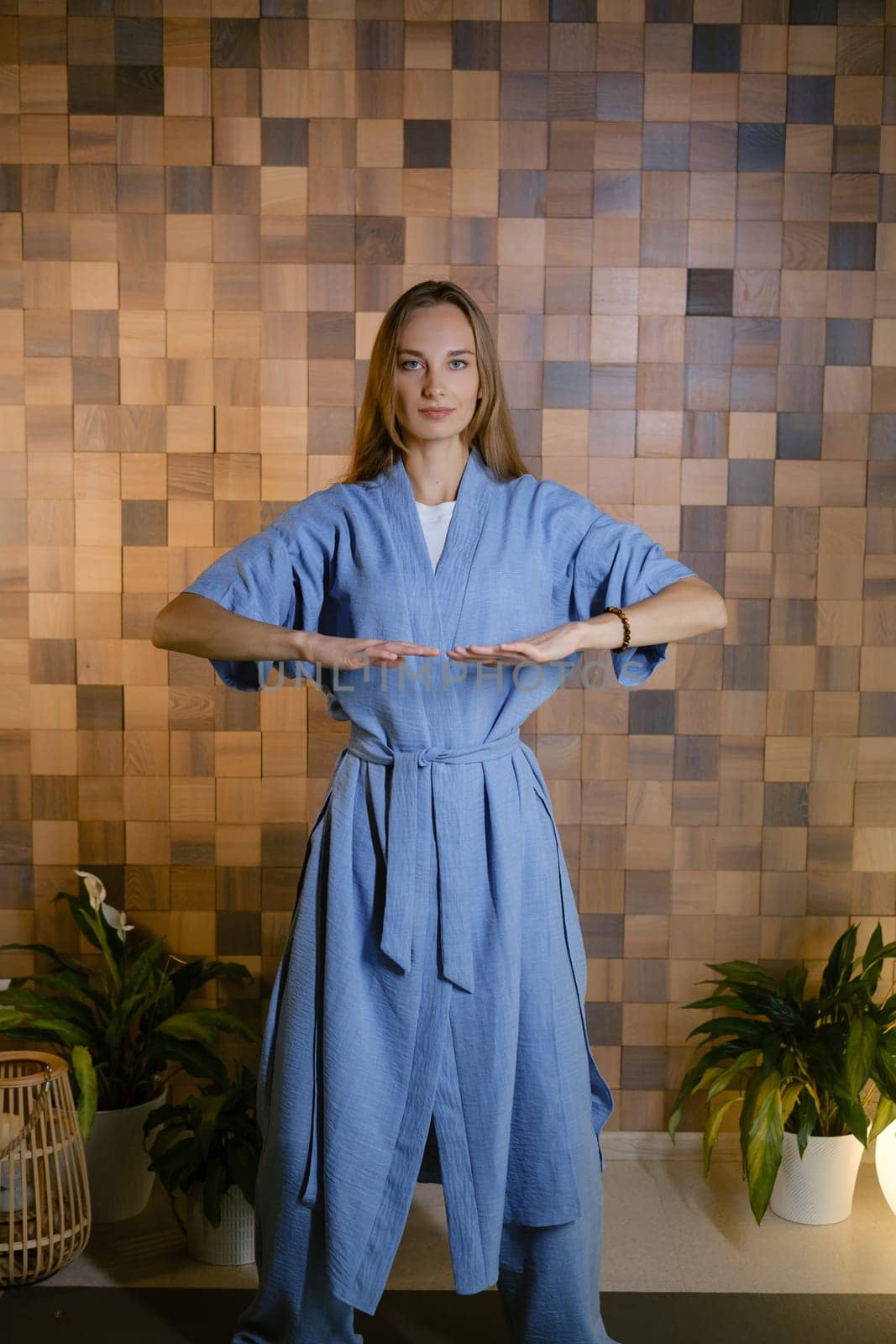 Girl in blue kimano practicing kundalini or qigong yoga in fitness gym . Spiritual energy, life force located at the base of the spine.