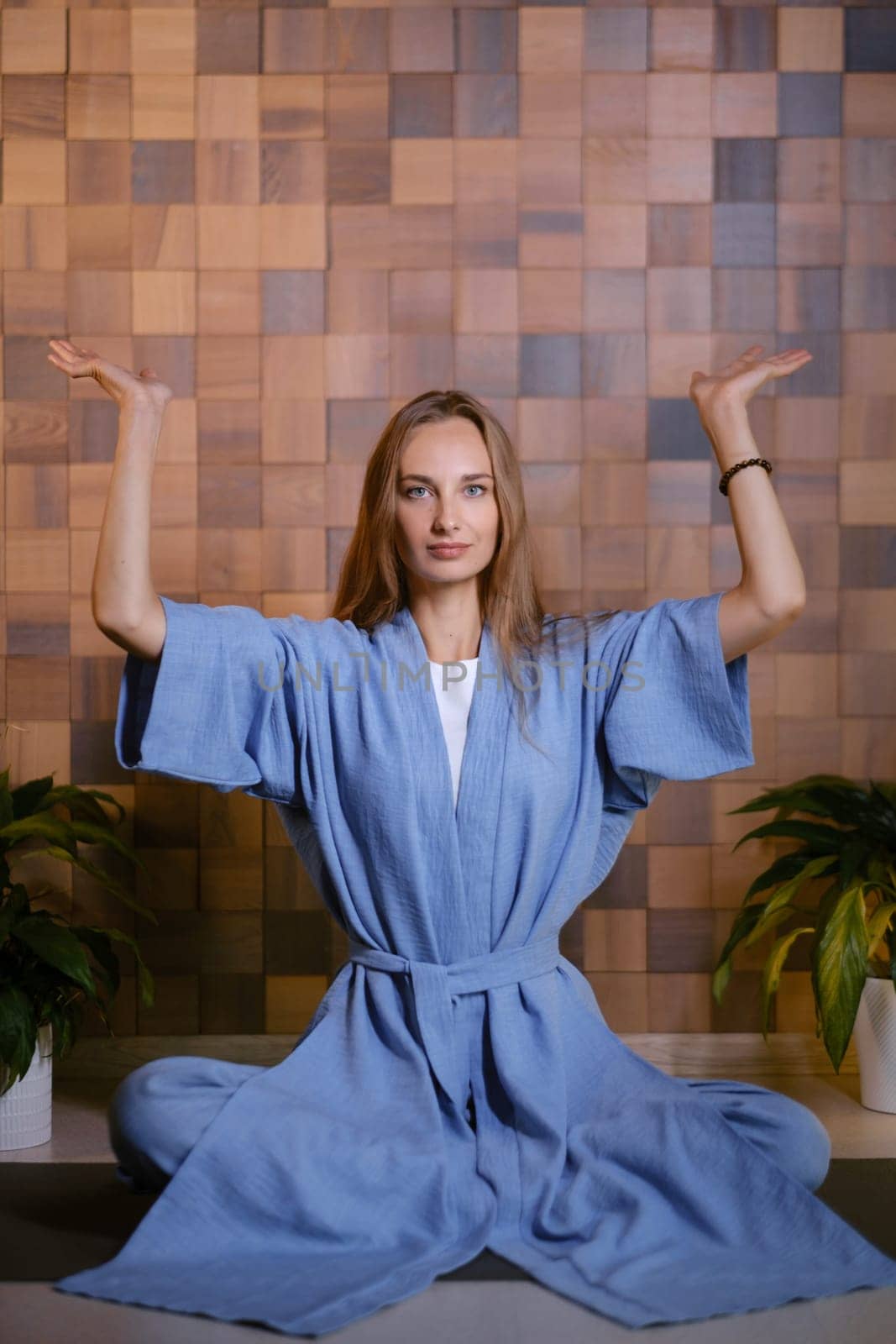 Girl in blue kimano practicing kundalini or qigong yoga in fitness gym . Spiritual energy, life force located at the base of the spine.