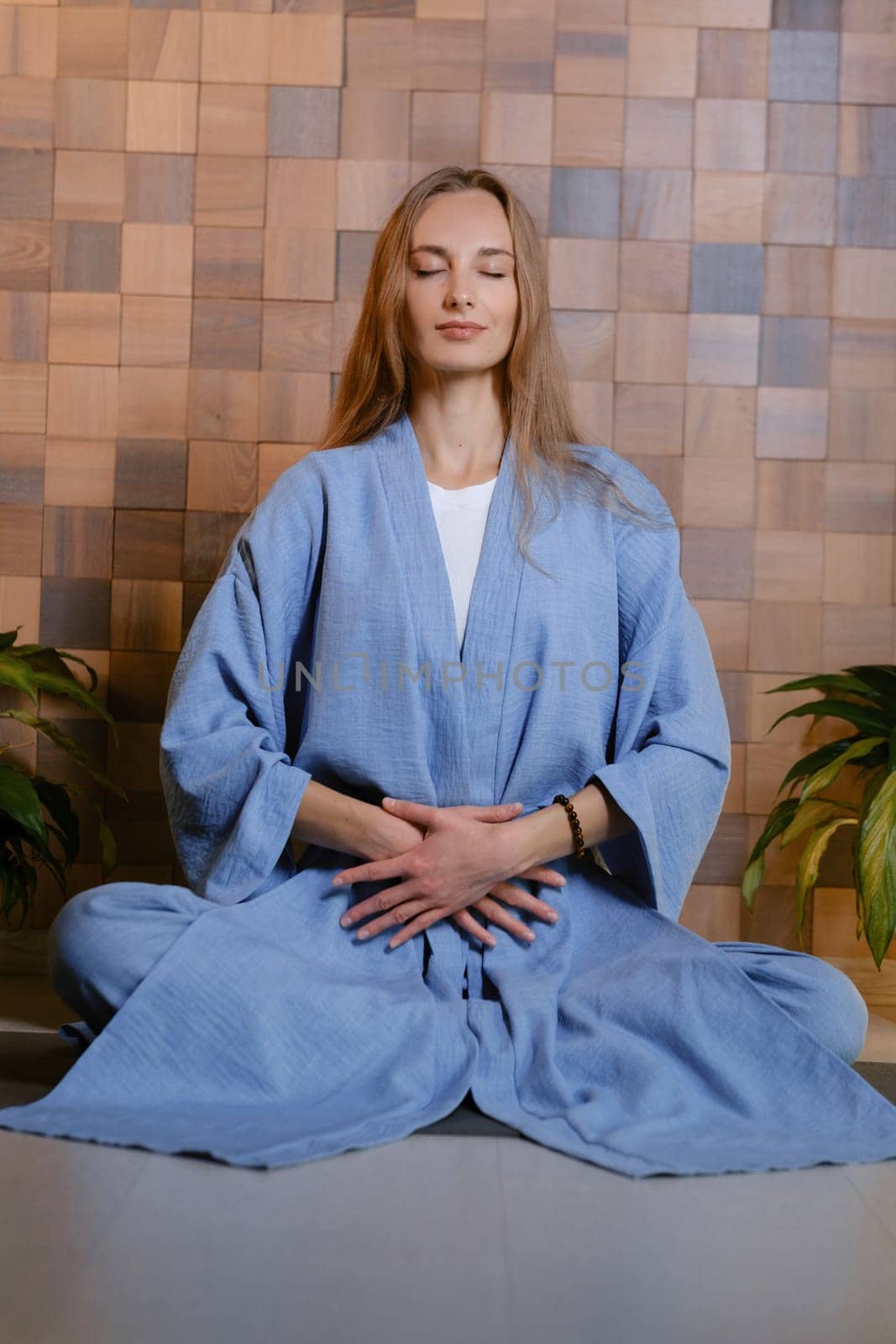 Girl in blue kimano practicing kundalini or qigong yoga in fitness gym . Spiritual energy, life force located at the base of the spine.