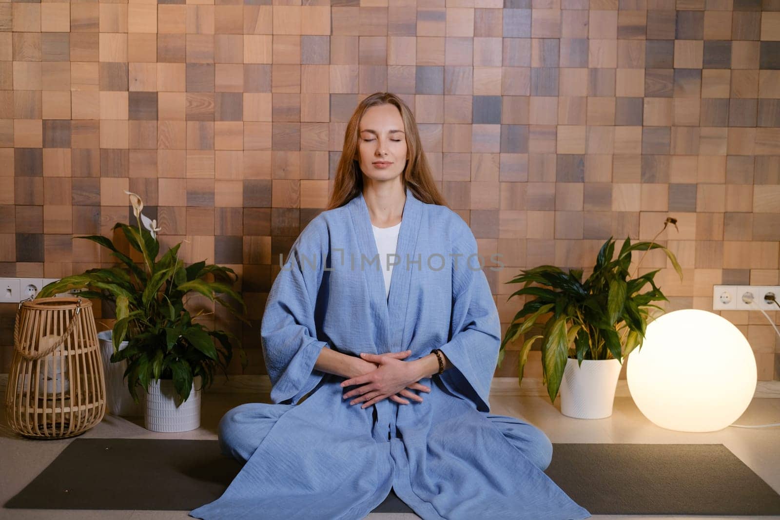 Girl in blue kimano practicing kundalini or qigong yoga in fitness gym . Spiritual energy, life force located at the base of the spine.