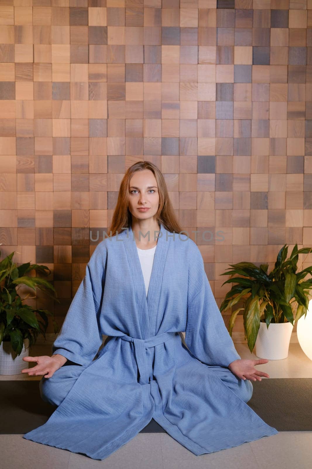 Girl in blue kimano practicing kundalini or qigong yoga in fitness gym . Spiritual energy, life force located at the base of the spine.