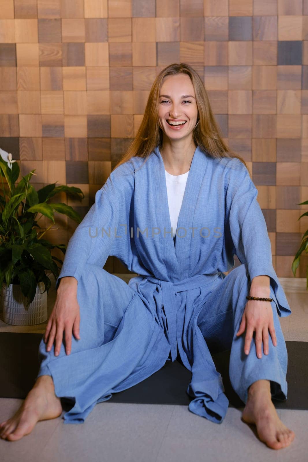 Girl in blue kimano practicing kundalini or qigong yoga in fitness gym . Spiritual energy, life force located at the base of the spine.