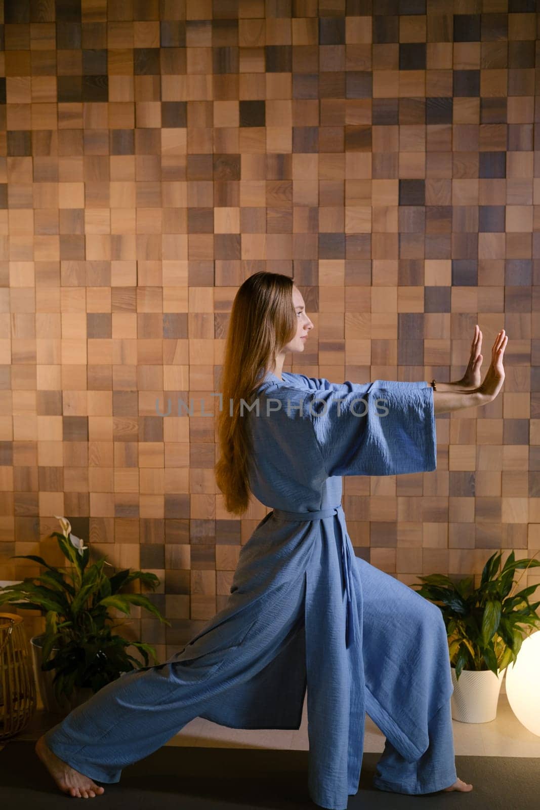 Yoga instructor in blue kimano at fitness gym . The girl does qigong yoga. The exercises are based on the movement of internal energy, the system of channels, energy centers, chakras.