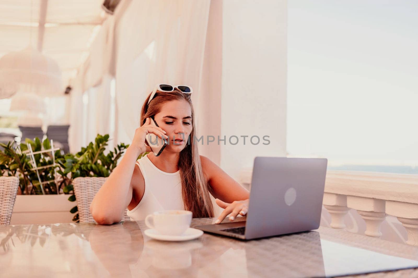 Woman coffee cafe macbook. Woman sitting at a coffee shop with mobile phone drinking coffee and looking away. Caucasian female relaxing at a cafe
