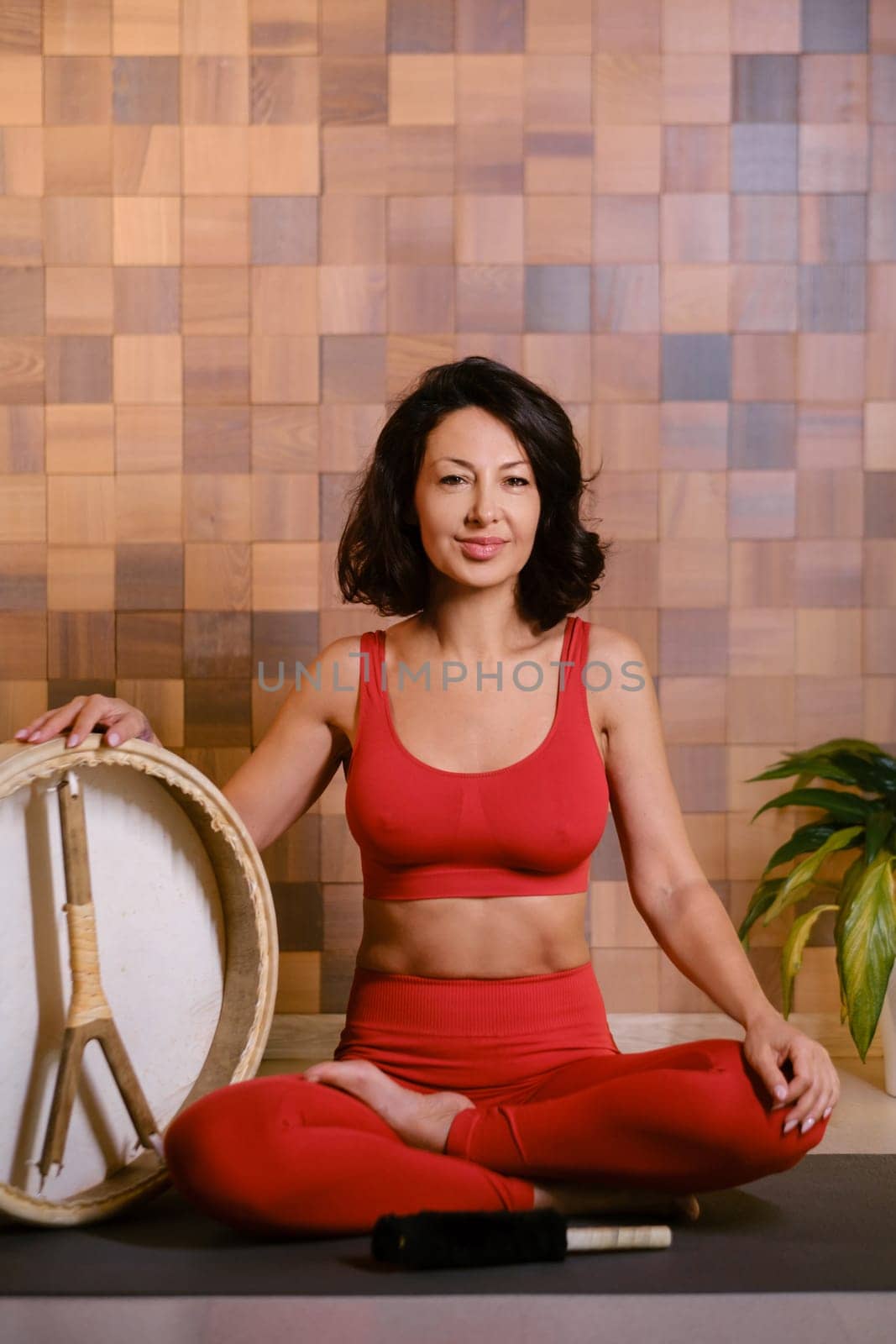 Portrait of an athletic woman with a tambourine in the gym. Kalimeditation class.