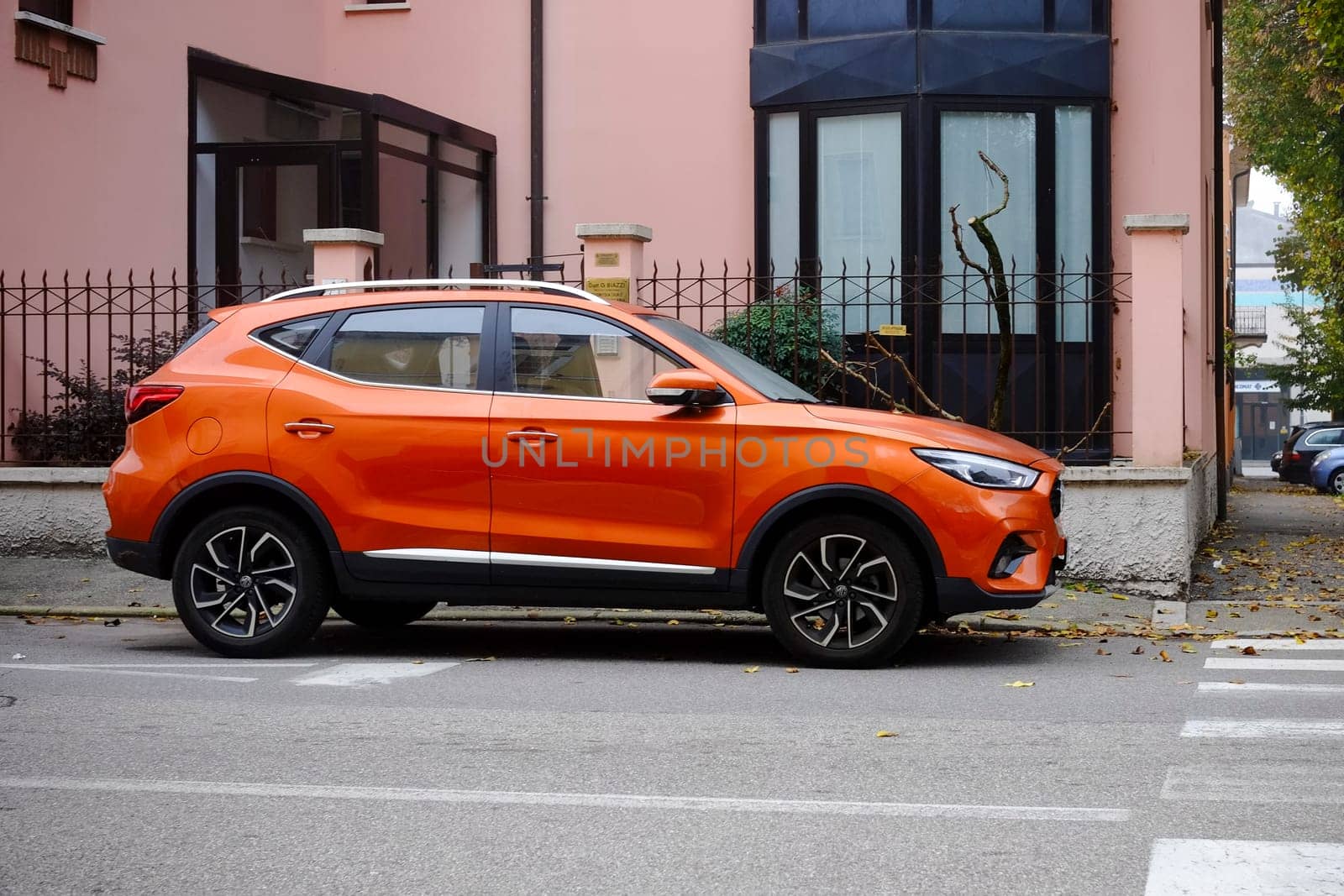 Cremona, Itally - October 6th 2024 Sleek and vibrant: a modern orange mg zs ev suv on a residential street, showcasing its stylish design and bold color