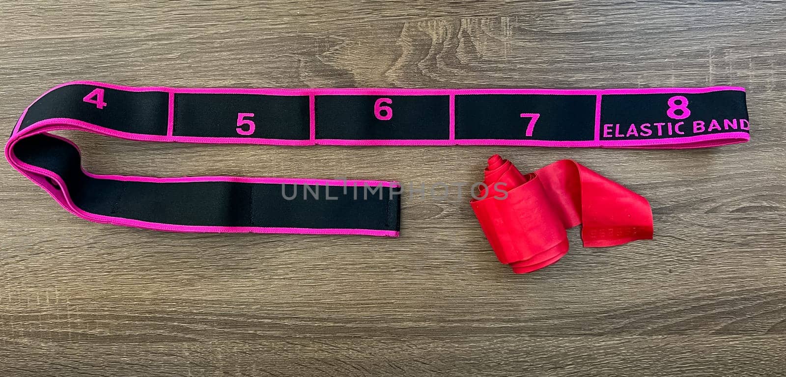 Elastic resistance band with numbered sections for versatile workout routines, placed on a wooden table. Ideal for strength training, stretching, and fitness exercises.