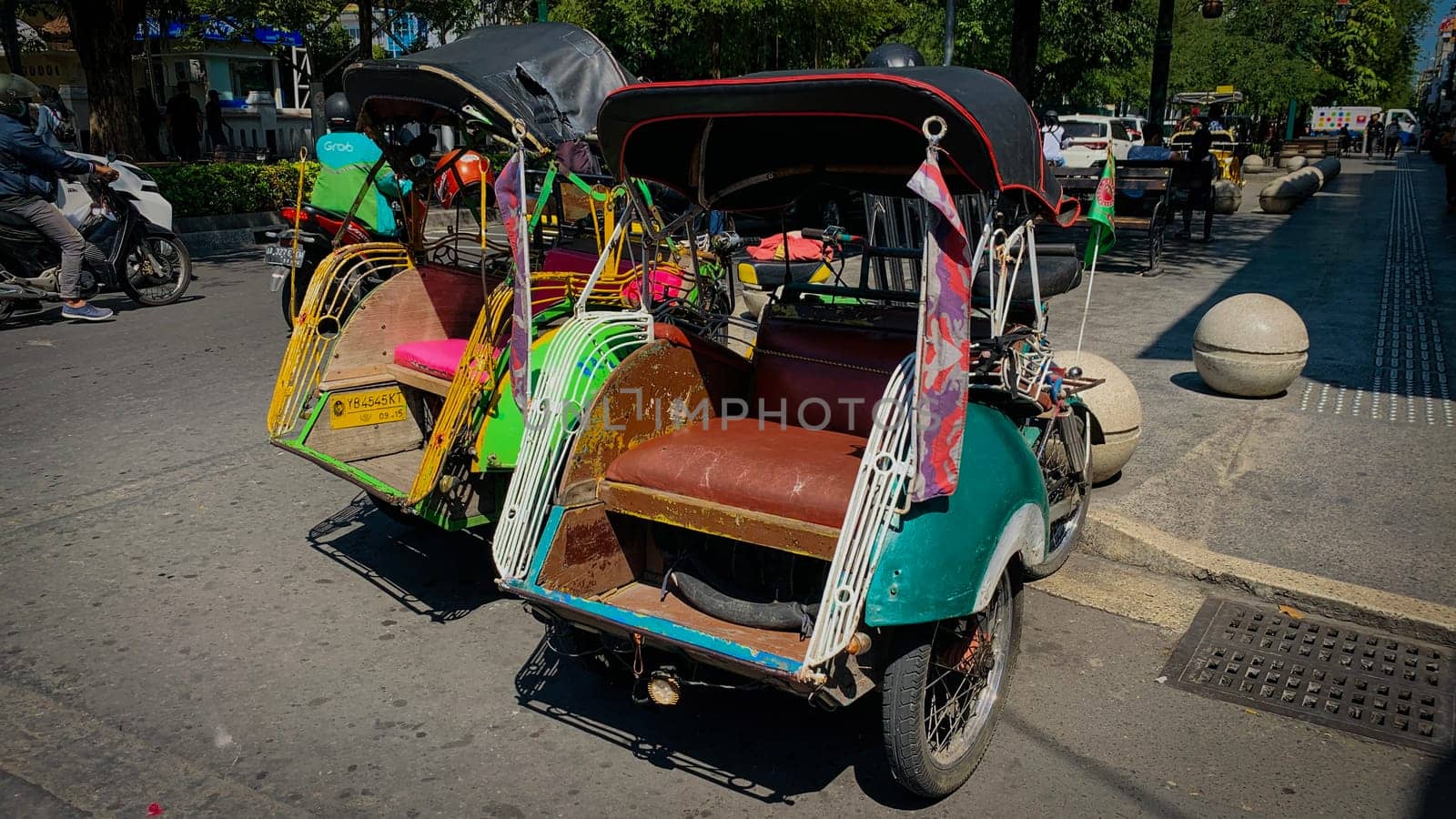 pedicab or rickshaw or locals calls it becak with a canopy is parked on a sunny street, reflecting a vibrant urban scene. The vehicle features a padded seat and unique design
